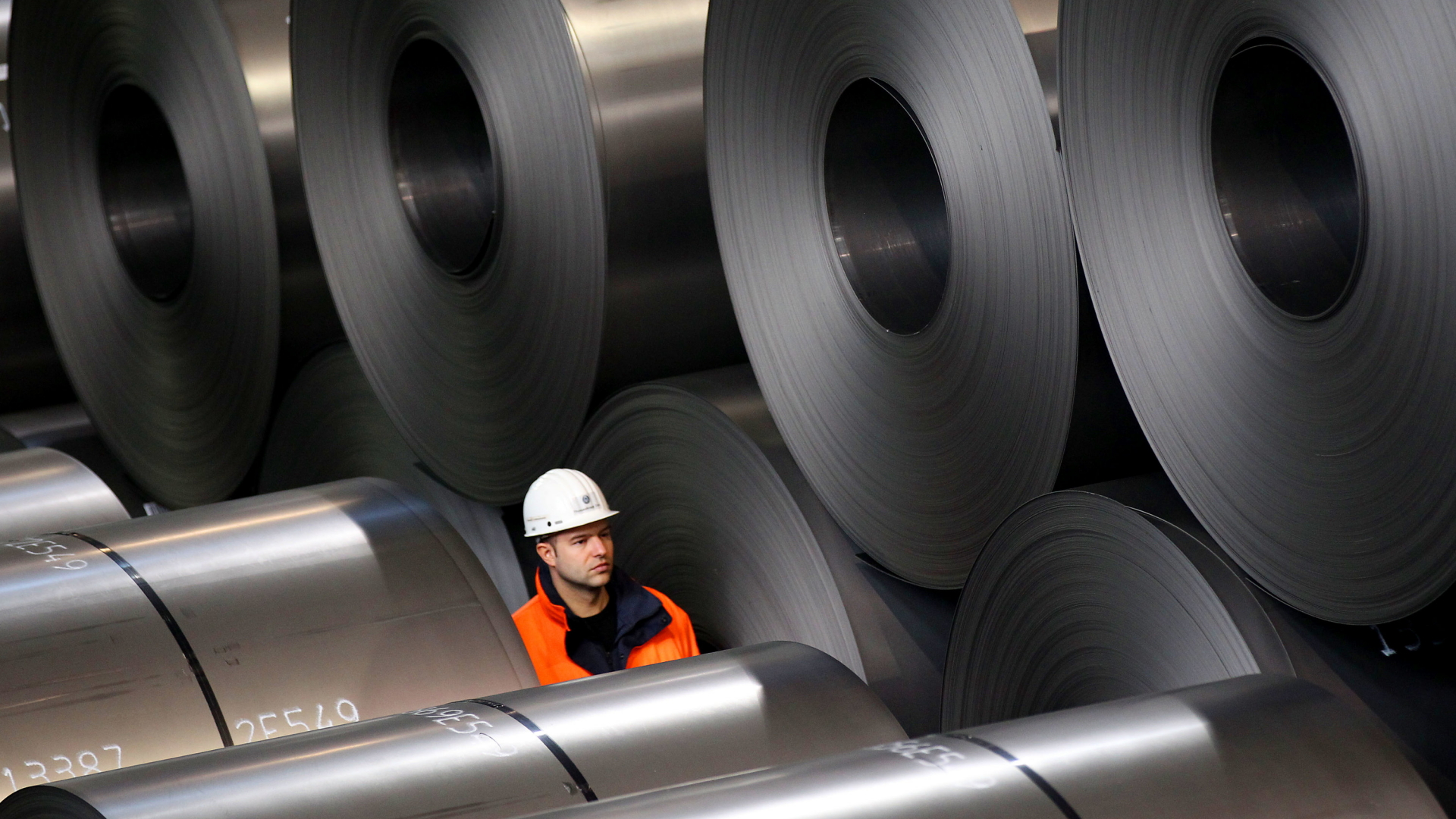  Ein Mitarbeiter von Thyssenkrupp geht im Stahlwerk in Duisburg an Rohstahlrollen vorbei. | dpa