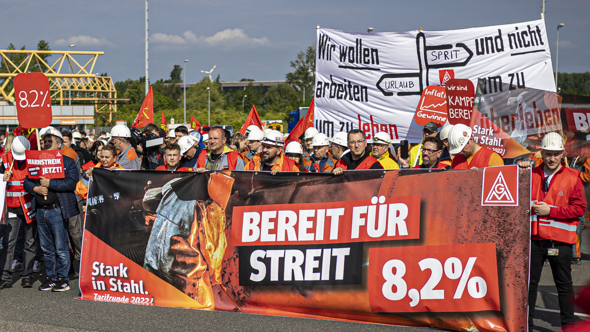Stahlarbeiter halten bei einem Warnstreik Transparente mit ihrer Lohnforderung