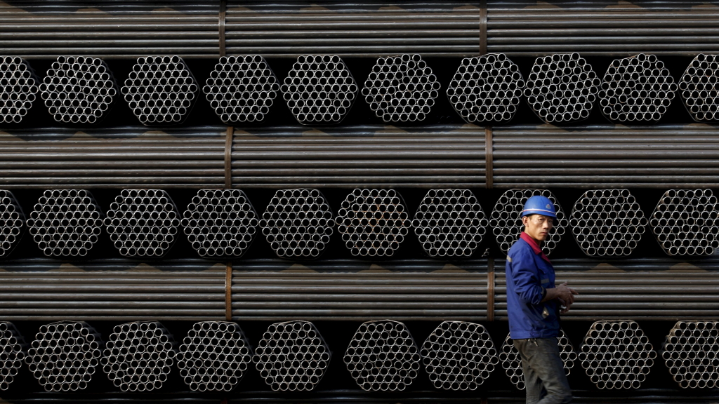 Ein chinesischer Arbeiter vor einem Stapel von Stahlrohren.