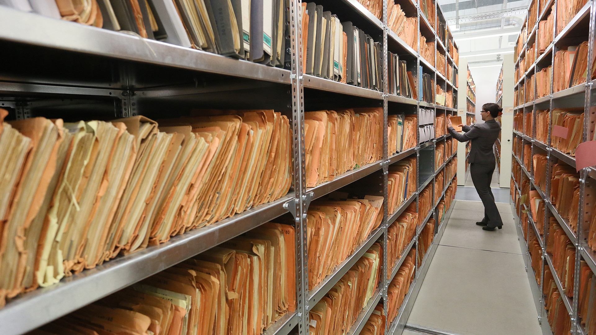 Eine Mitarbeiterin steht im Stasi-Archiv zwischen Regalen mit bisher nicht erfassten Unterlagen. | dpa