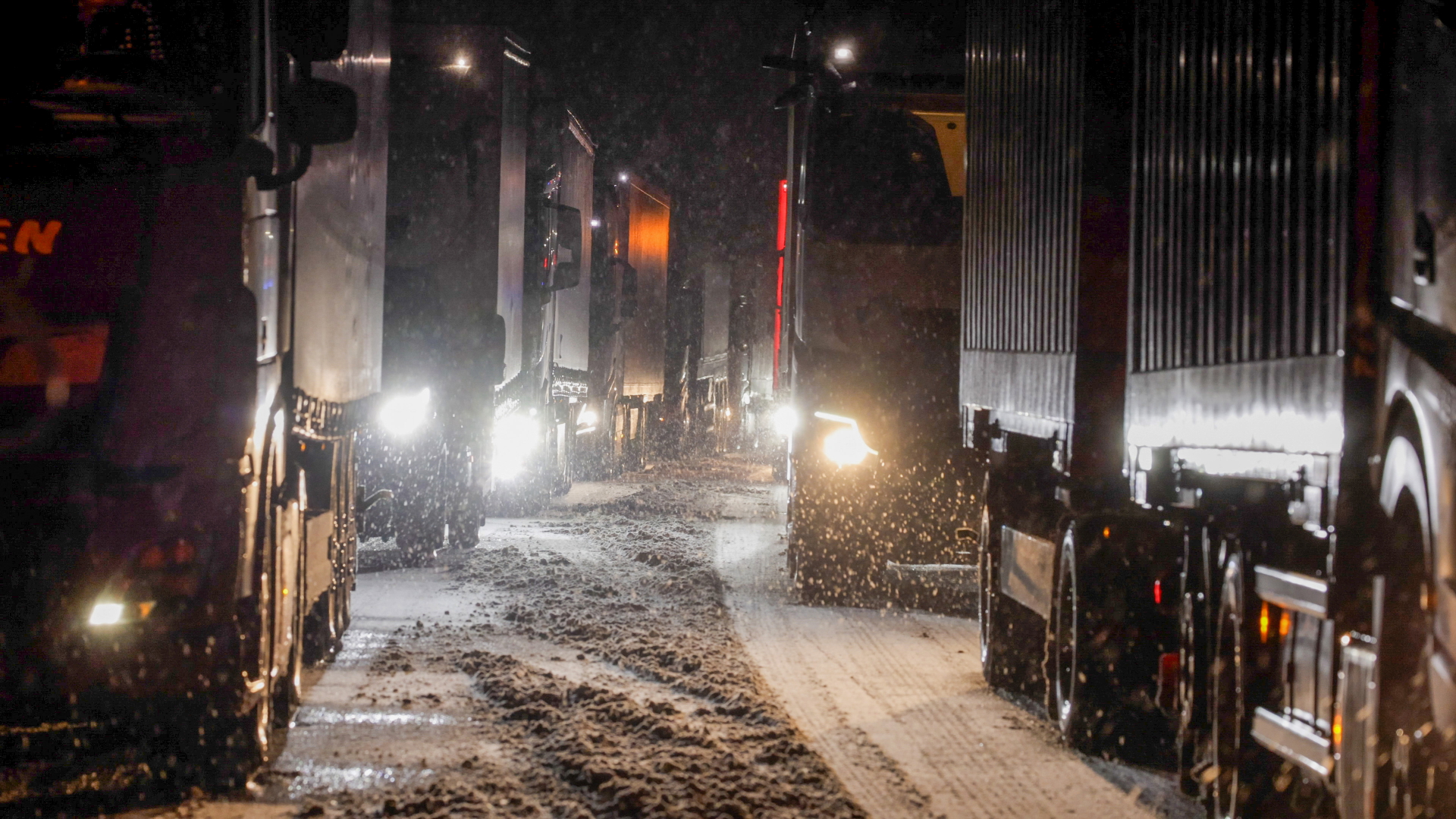 Lastkraftwagen stauen sich auf der Autobahn A5 bei Grünberg auf schneebedeckter Fahrbahn. 