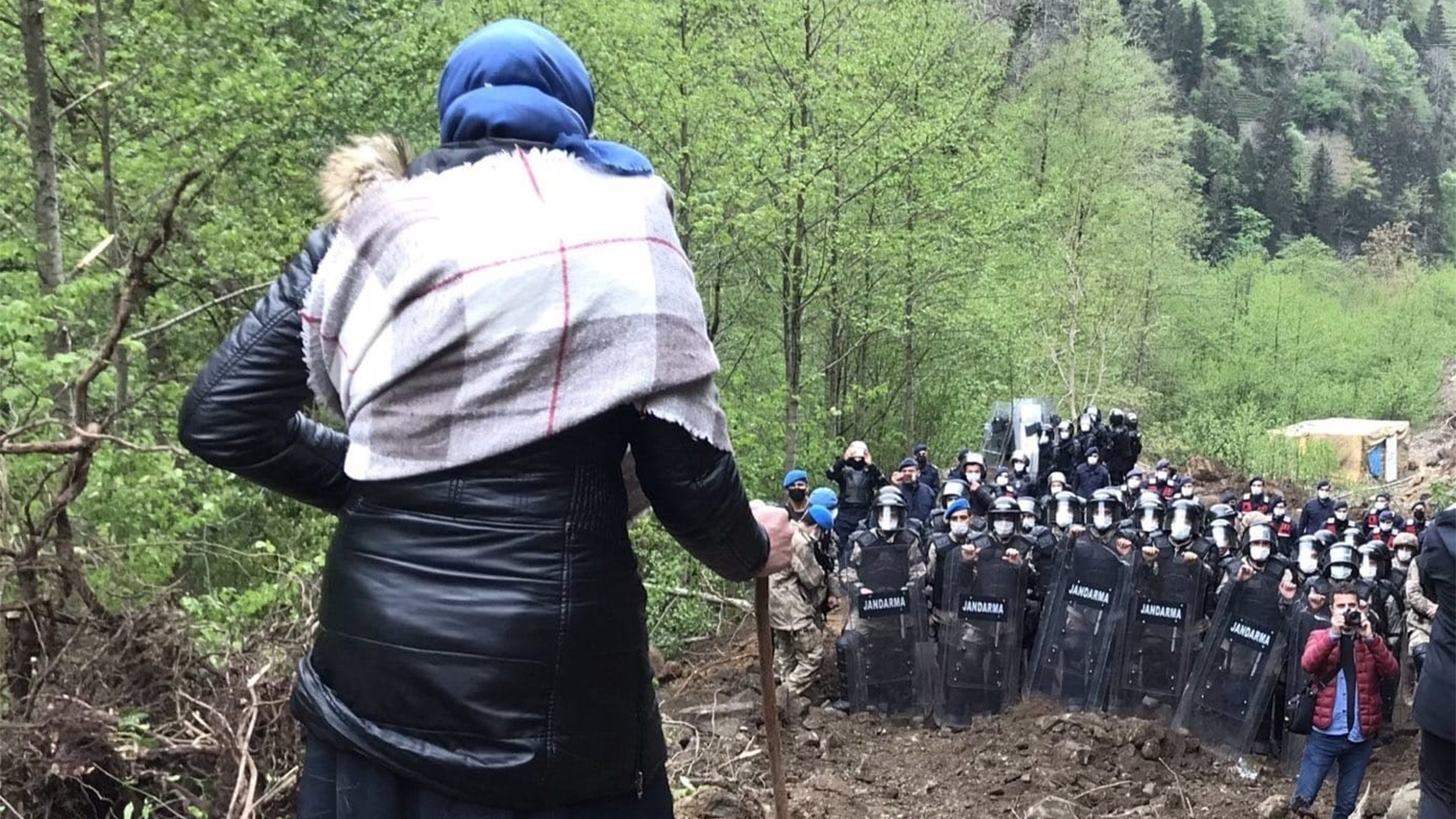 Mehrere Polizisten stehen vor einer protestierenden Frau im Steinbruch.