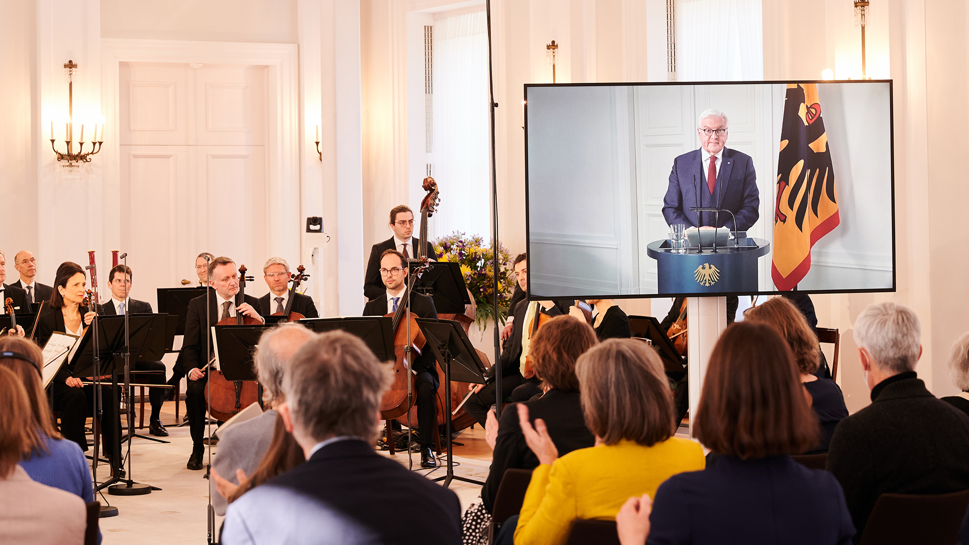 Die Berliner Philharmoniker sitzen im Schloss Bellevue vor ein paar Dutzend Zuschauern während Frank-Walter Steinmeier wegen Krankheit per Video zugeschaltet ist. | dpa