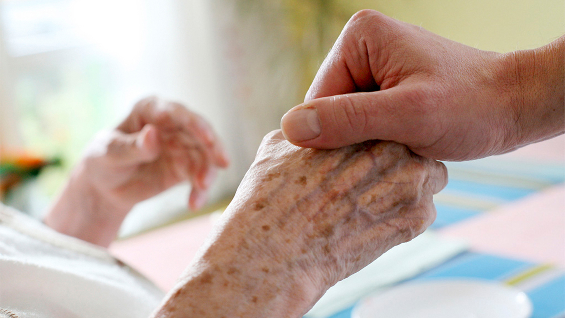 Eine Hand berührt die eines älteren Patienten. | dpa