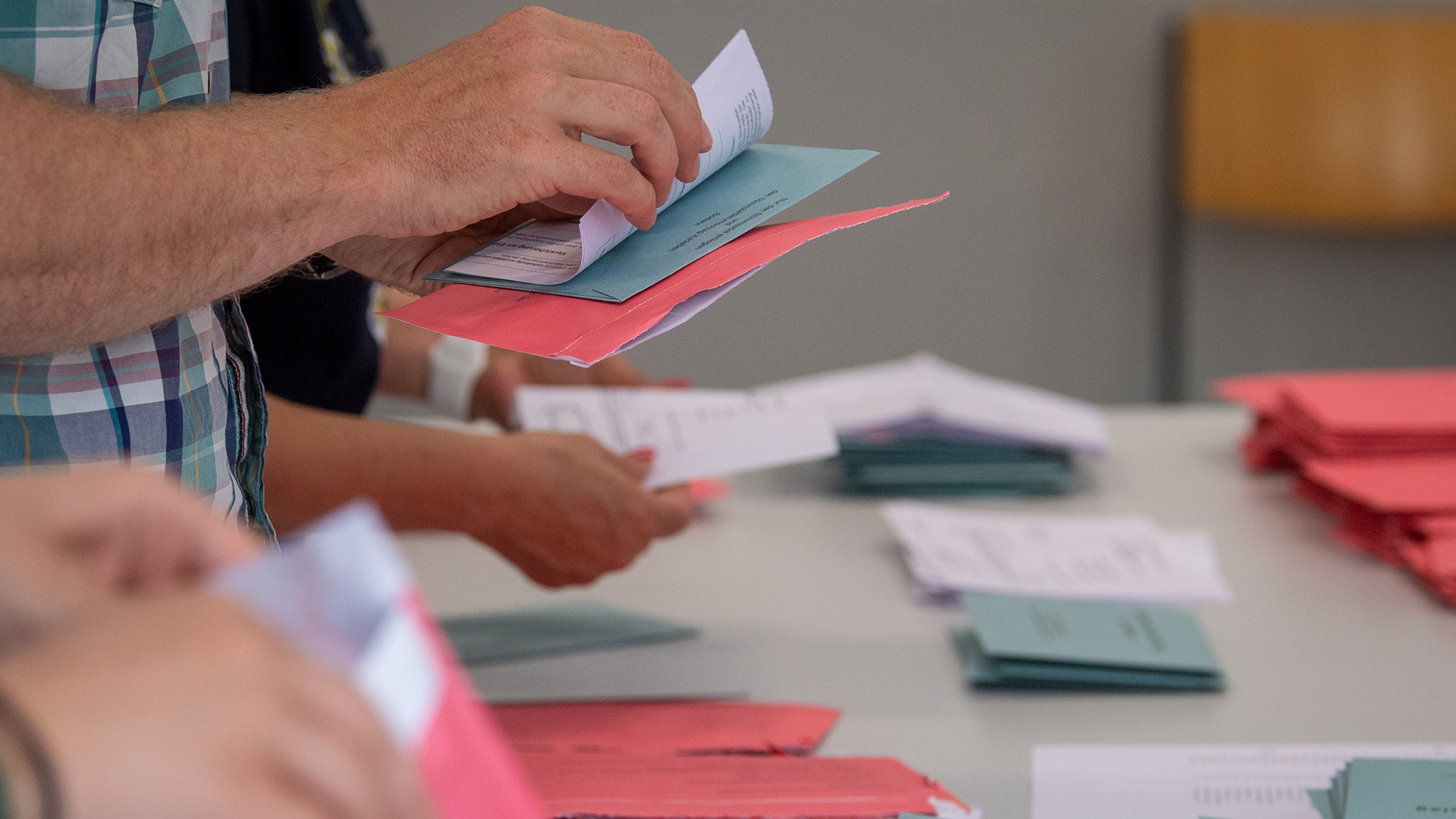 Wahlhelfer und Wahlhelferinnen öffnen im Klassenzimmer einer Schule in Magdeburg die Umschläge der Briefwahl. | dpa