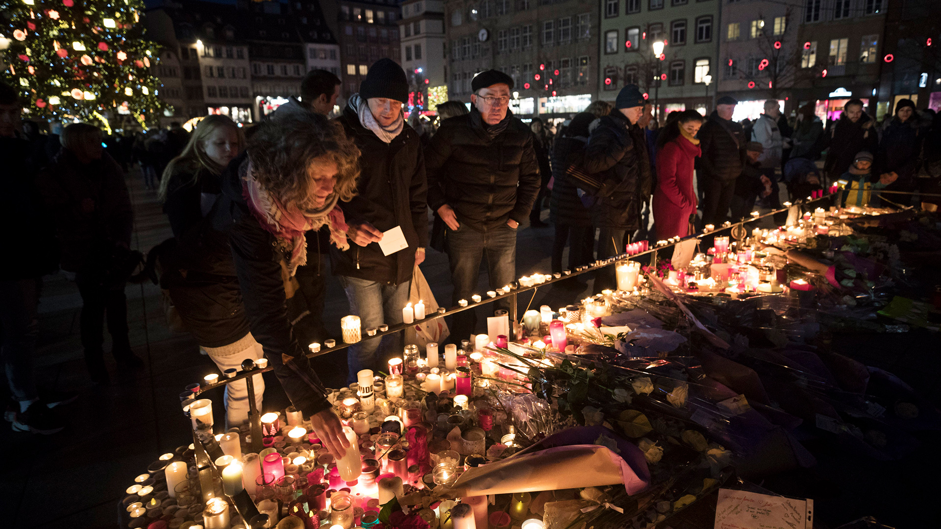 In Gedenken an die Opfer von Straßburg zünden Menschen in der elsässischen Metropole Kerzen an. | Bildquelle: AP
