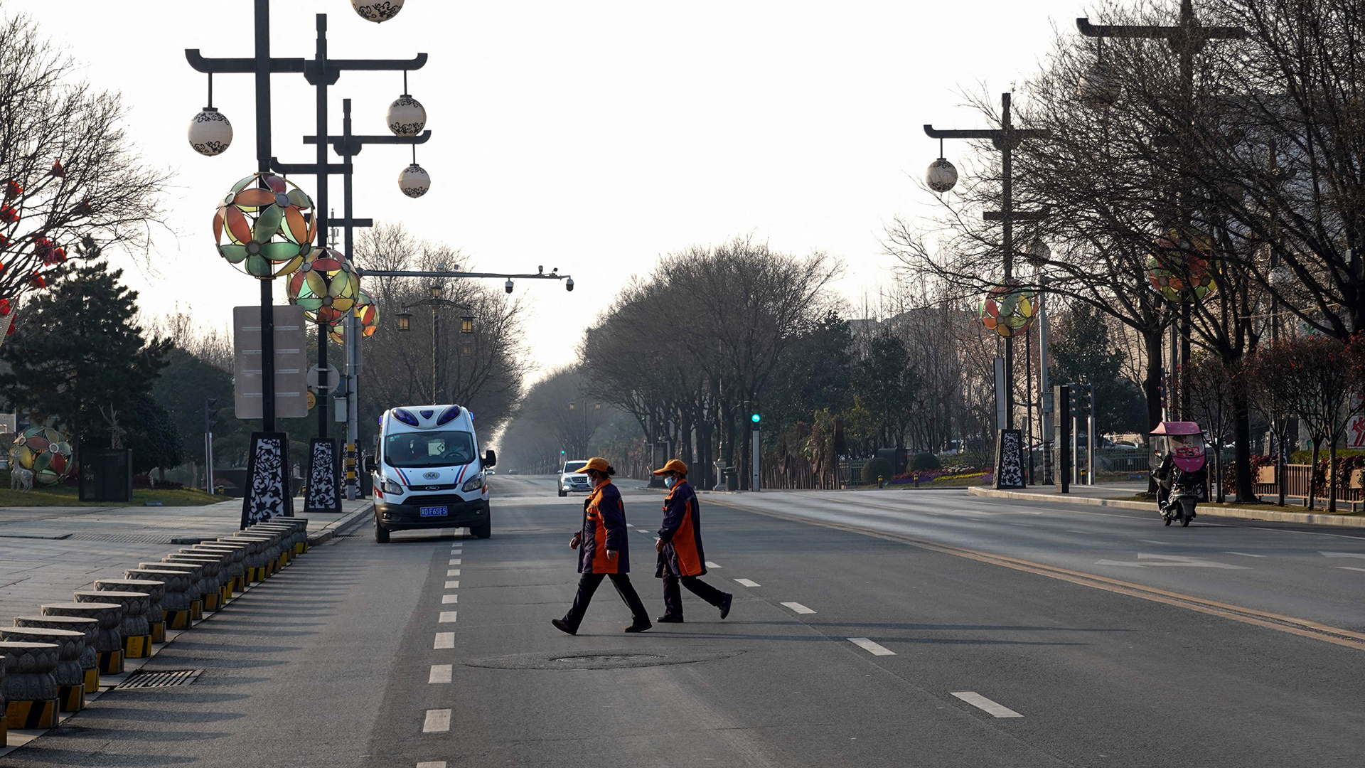 Menschen überqueren eine leere Straße in Xi'an (China). | AFP