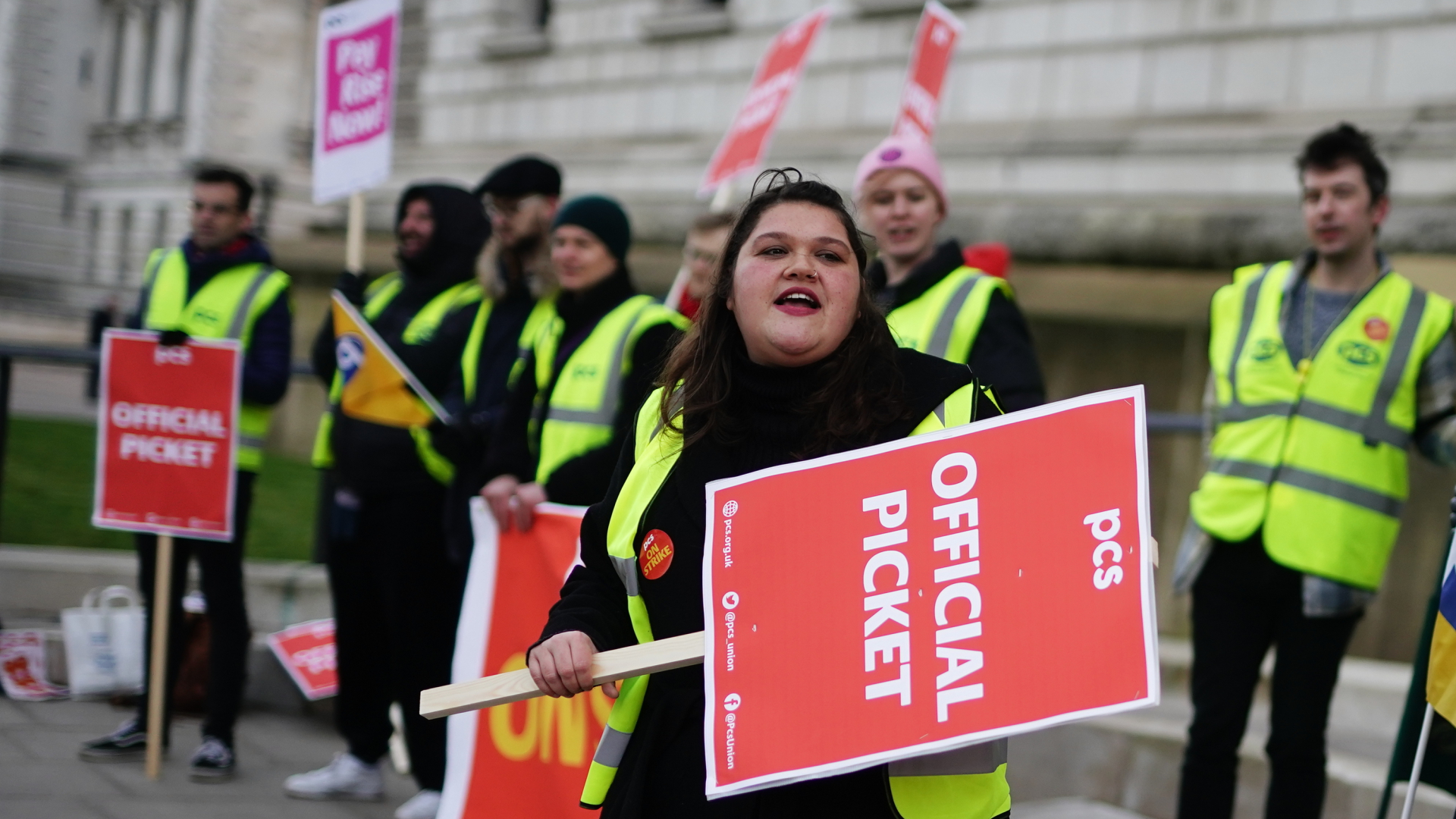 Mitglieder der Gewerkschaft für öffentliche und kommerzielle Dienste (PCS) stehen an einem Streikposten vor dem Büro des britischen Finanzministeriums. | dpa
