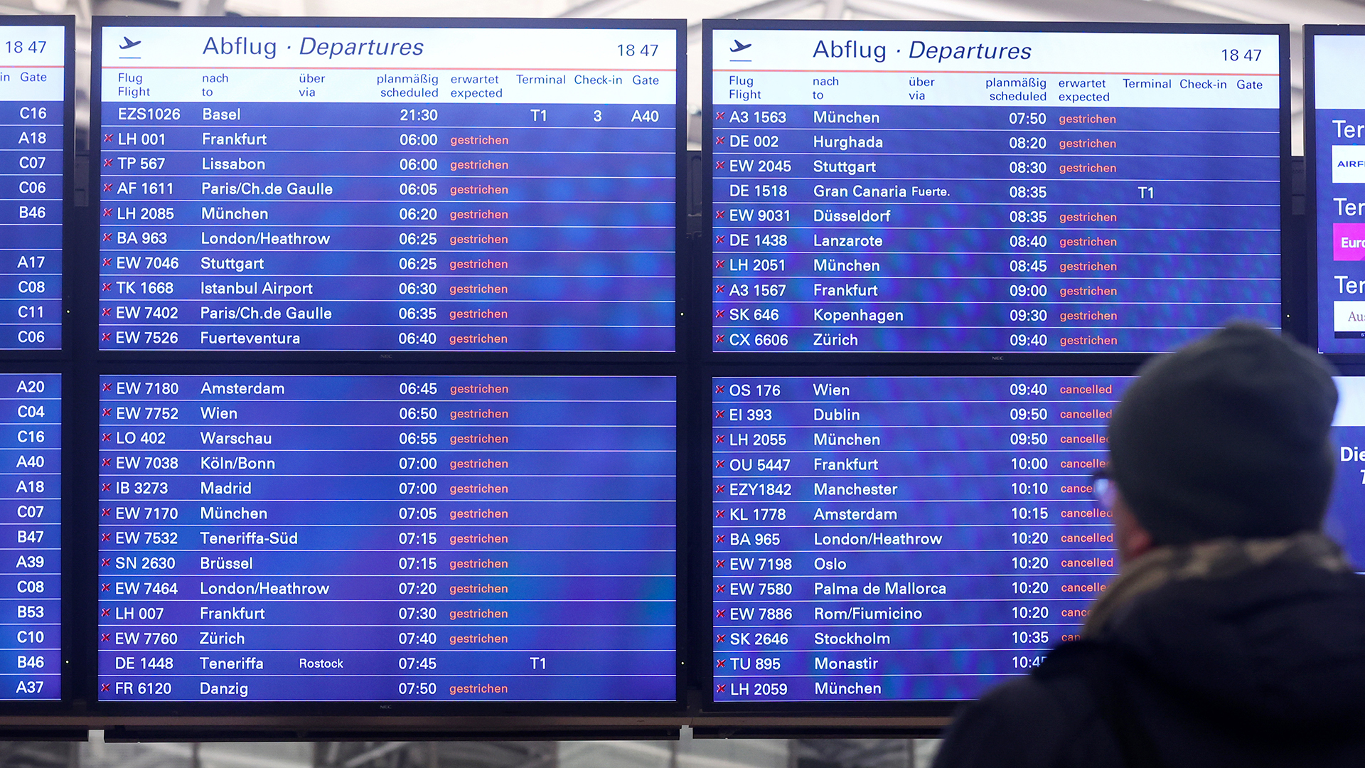 Ein Mann schaut am Flughafen Hamburg auf eine Anzeigentafel, auf der zahlreiche gestrichene Flüge angezeigt werden. | picture alliance/dpa/Bodo Marks