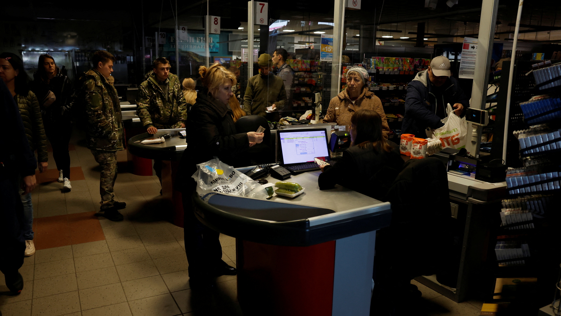 Menschen kaufen in einem wegen eines Stromausfalls im Dunkeln liegenden Supermarkts in Charkiw ein.  | REUTERS