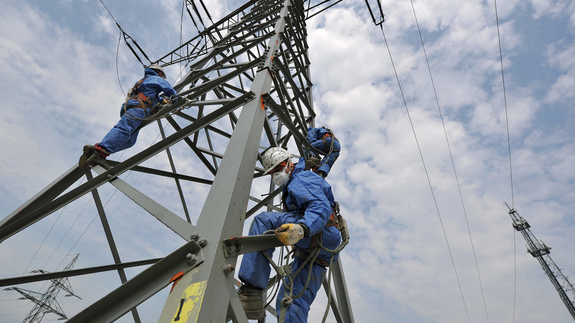 Polnische Arbeiter führen an einem Strommasten Entrostungsarbeiten durch