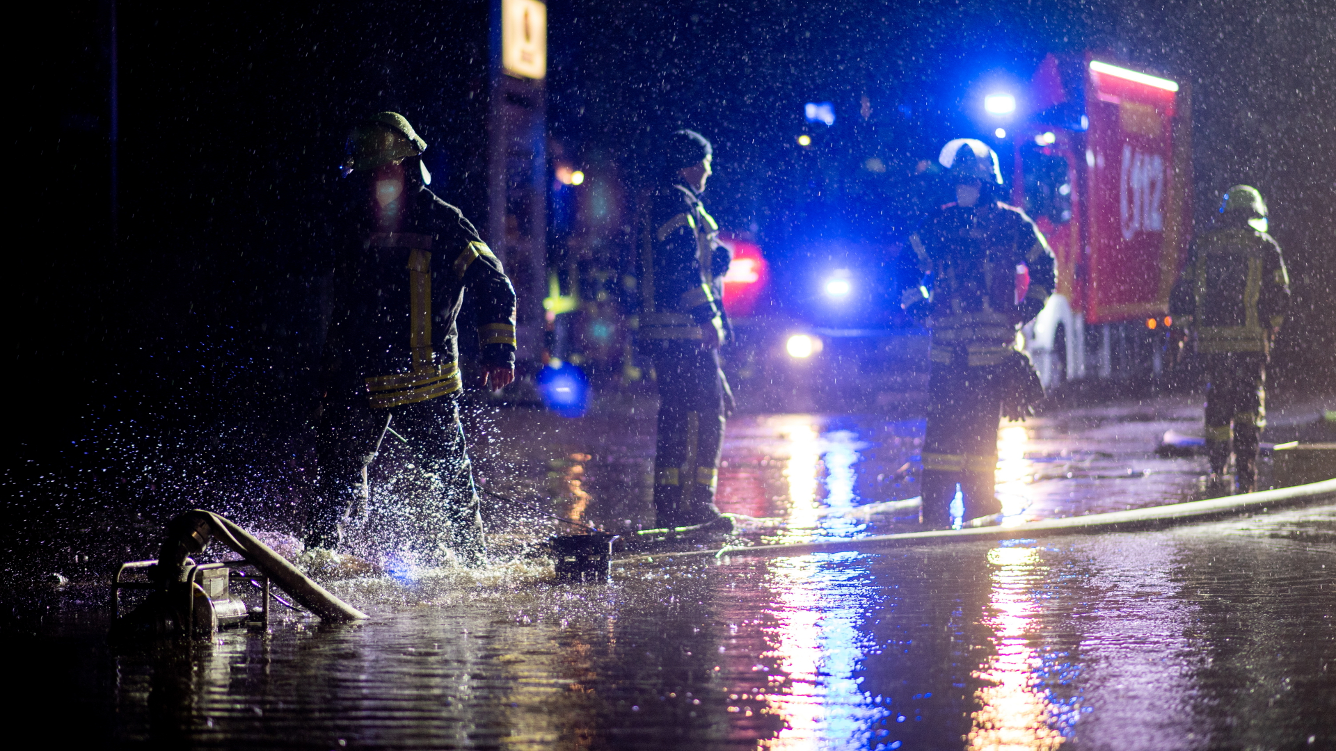 Einsatzkräfte der Feuerwehr pumpen das Wasser vom Hof einer Autowerkstatt ab. | dpa