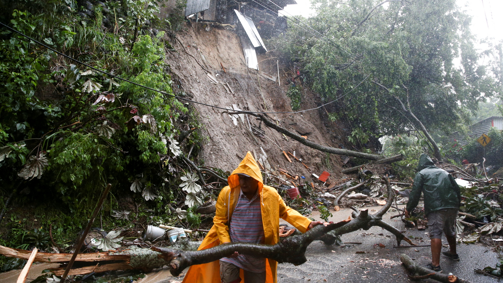 Männer räumen nach dem Durchzug des Sturms "Julia" eine Straße in El Salvador frei.  | REUTERS