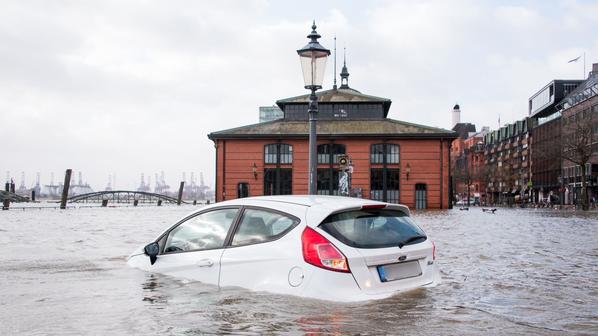 Ein Auto steht auf dem Fischmarkt mit der Fischauktionshalle während einer Sturmflut im Wasser der Elbe (Archivbild Januar 2022) | dpa