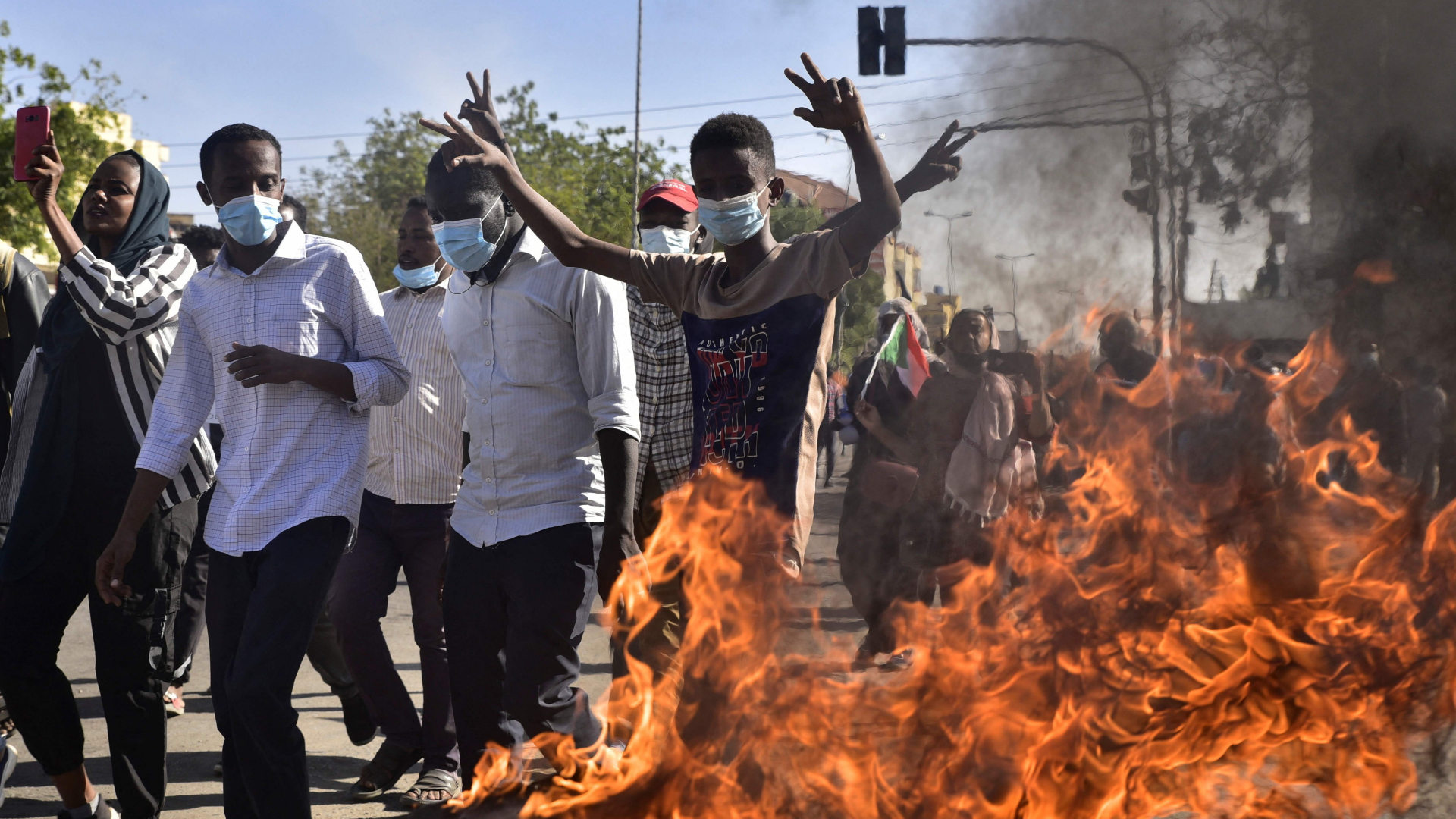 Demonstranten gehen an einem brennenden Autoreifen in Khartum vorbei. | AFP