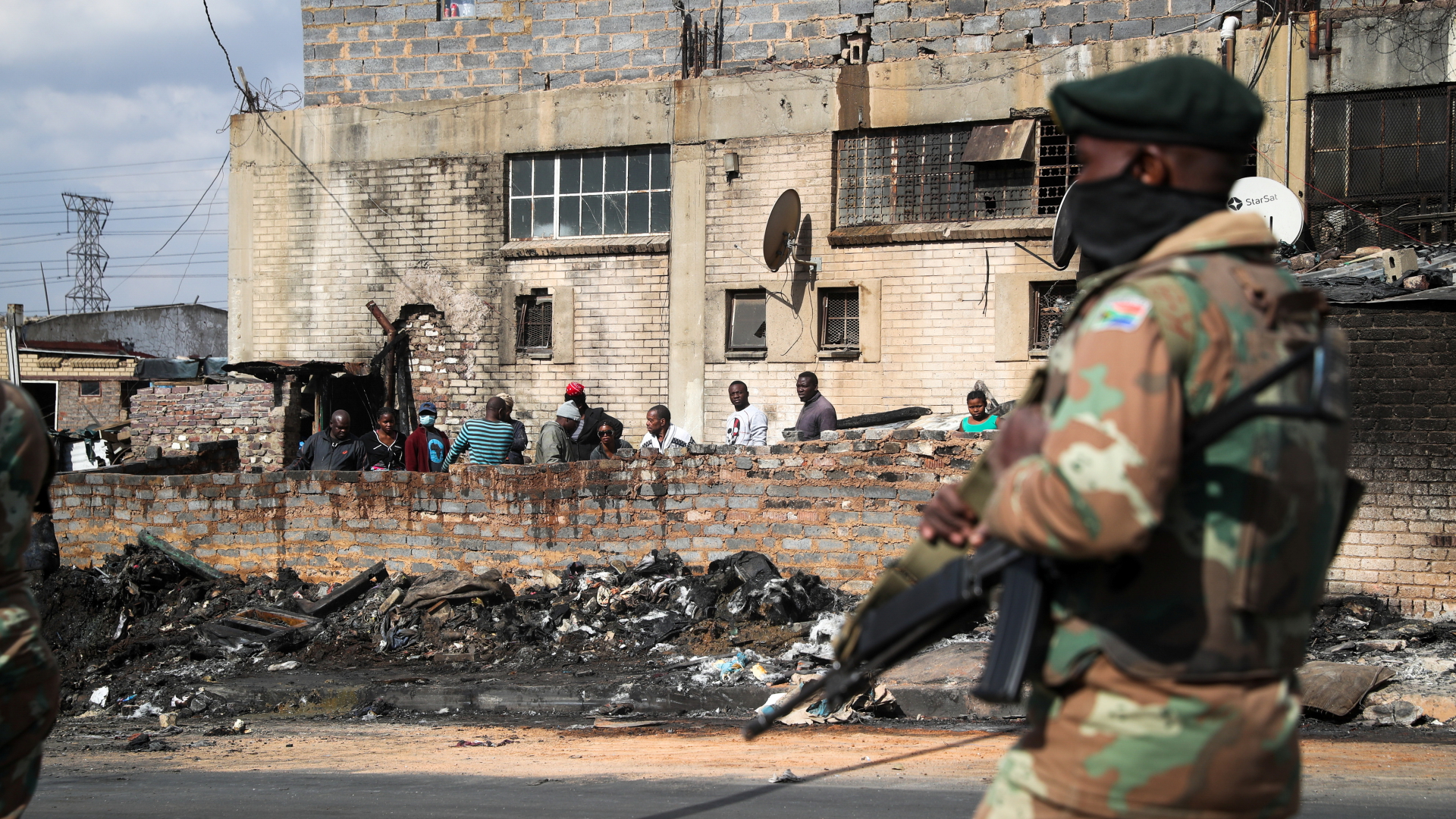 Ein Soldat patrouilliert vor einer Brandruine. | REUTERS
