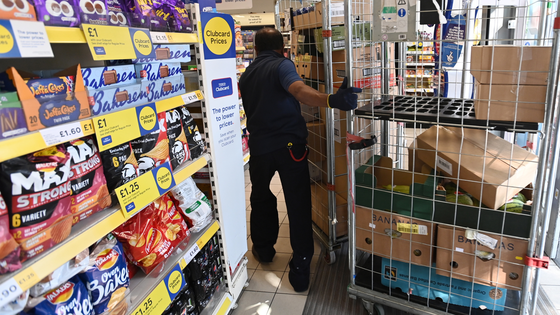 Ein Supermarktmitarbeiter bringt in London Produkte in ein Geschäft.