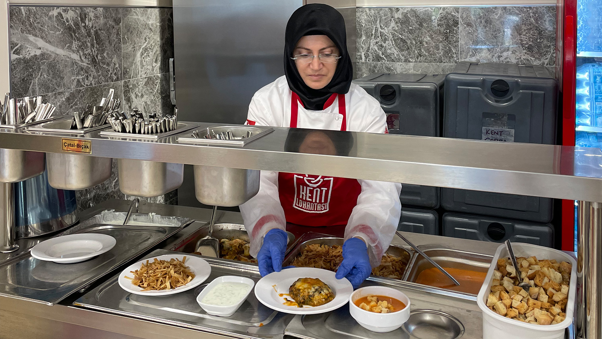 Eine Frau gibt in einer Suppenküche in der Türkei Essen aus. | Karin Senz