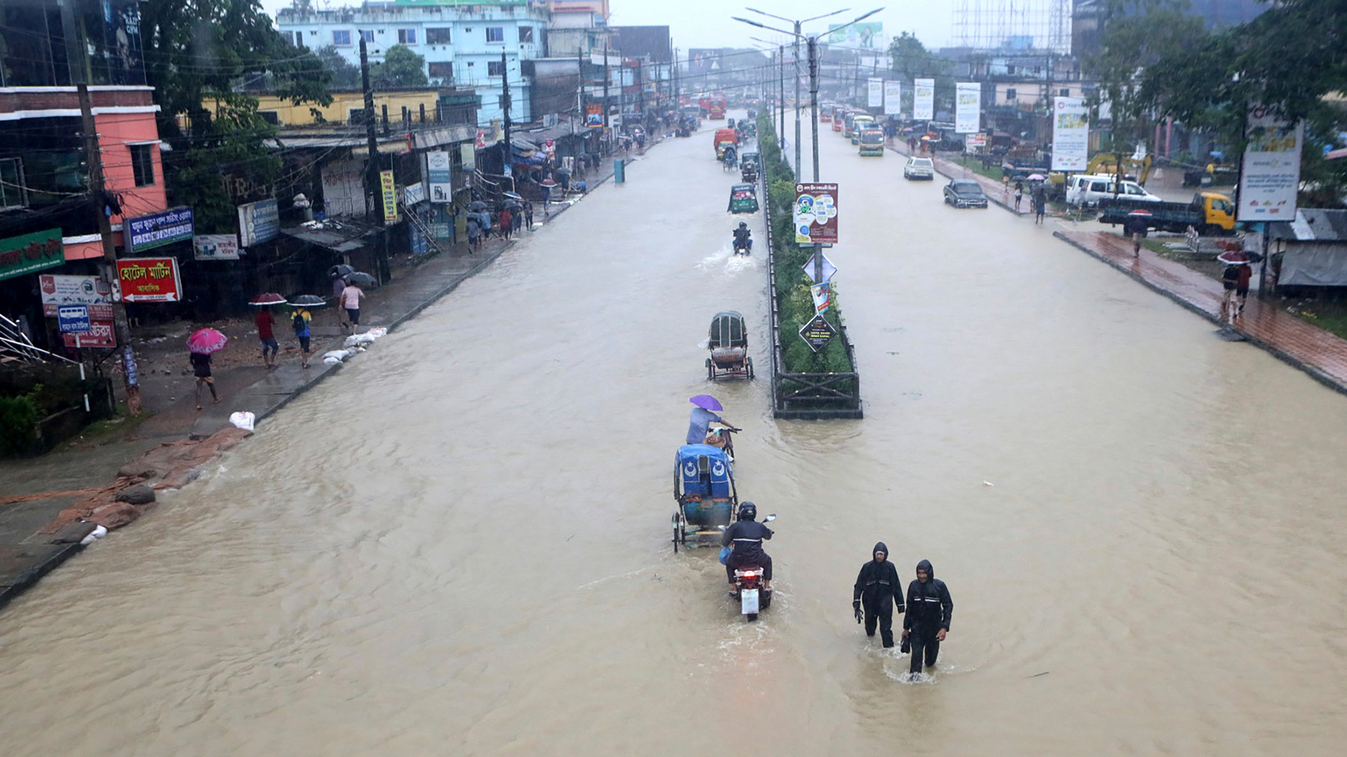Menschen waten durch eine überflutete Straße in Sylhet in Bangladesch. | AP