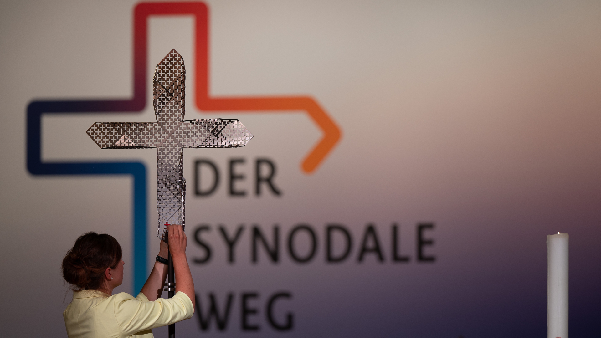 Eine Frau steckt während der vierten Synodalversammlung der katholischen Kirche in Deutschland im Congress Center Messe Frankfurt dem Synodalkreuz ein rotes kleines Kreuz an | dpa