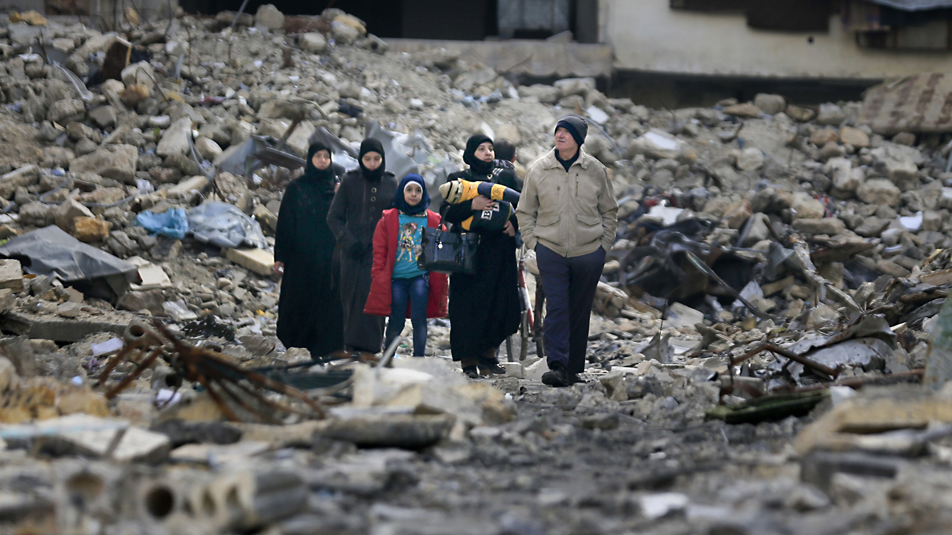 Anfang des Jahres in Aleppo. Eine Gruppe von Menschen betrachtet die Zerstörungen in der Stadt.