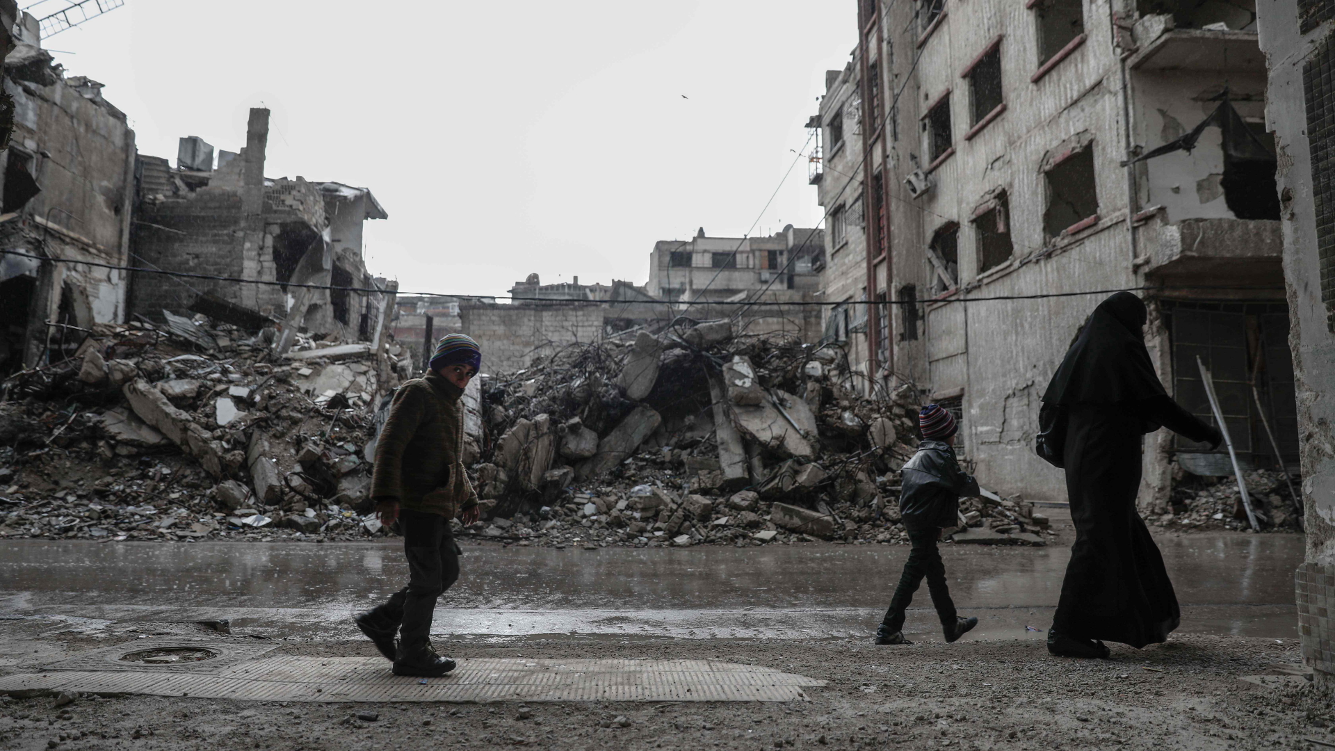 Menschen vor zerstörten Gebäuden in einem Vorort von Damaskus | AFP