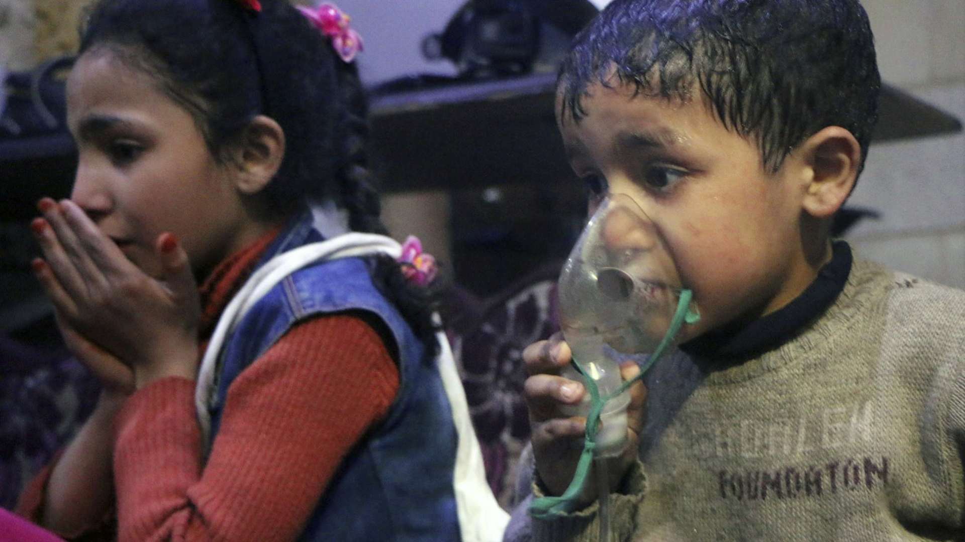 Das von der Hilfsorganisation Weißhelme veröffentlichte Foto zeigt einen kleinen Jungen, der sich eine Atemmaske auf das Gesicht drückt, neben ihm ein junges Mädchen. | dpa
