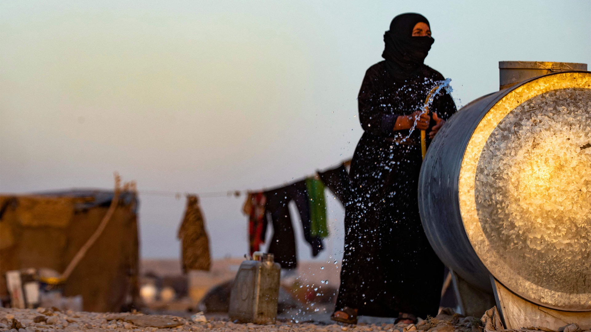 Eine Frau füllt einen Kanister mit Wasser im Flüchtlingscamp Sahlah al-Banat im Norden Syriens. | AFP