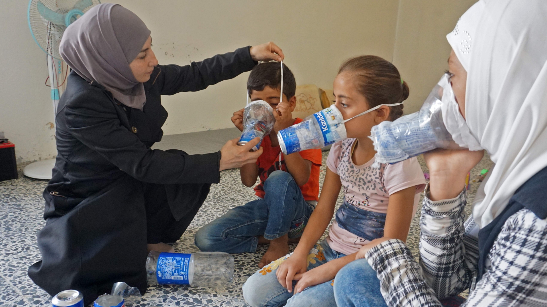Ein Frau und ihre Kinder in Idlib ziehen selbstgebaute Gasmasken über | AFP