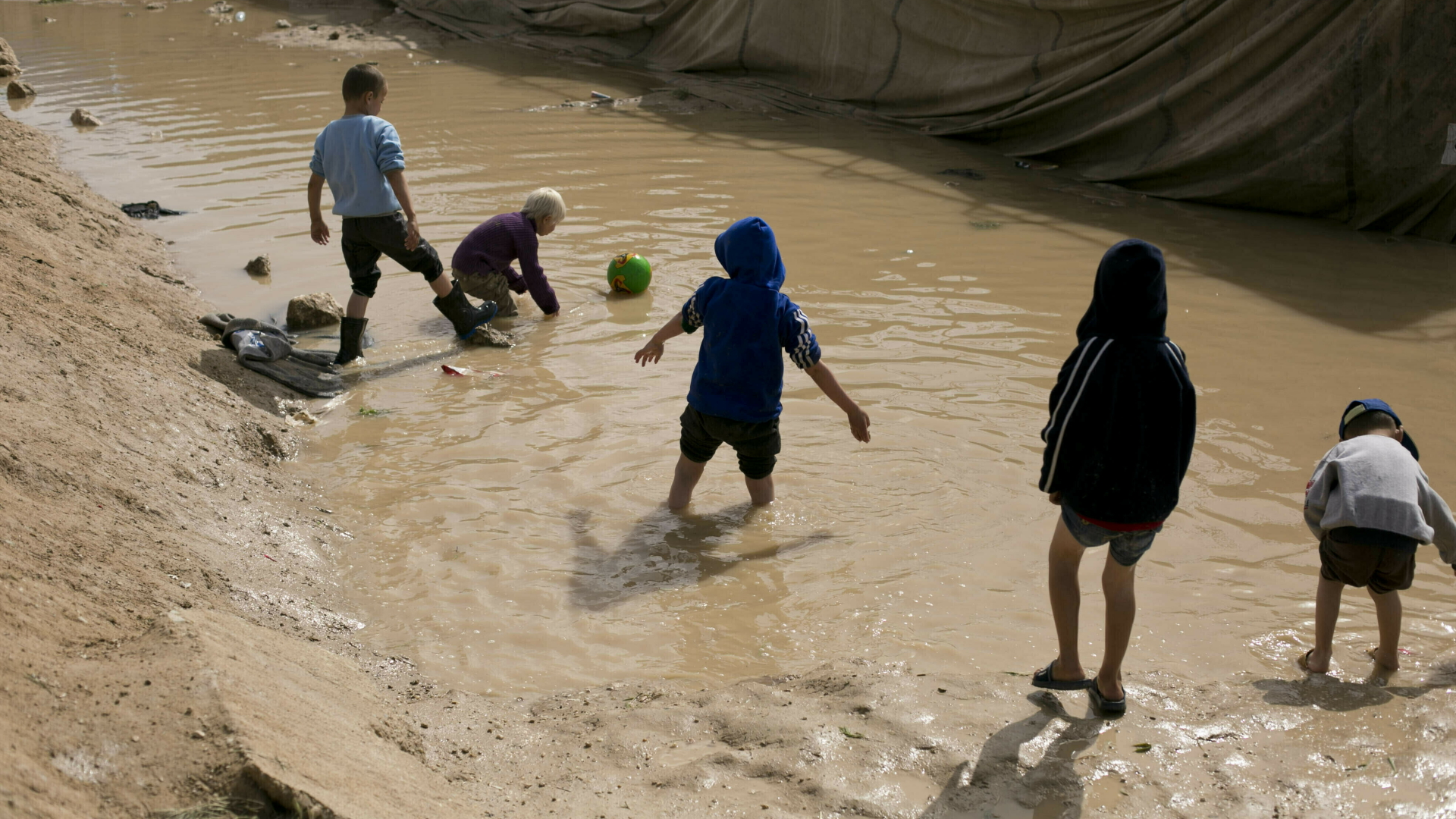 Kinder spielen in einer Schlammpfütze im Flüchtlingslager Al-Hol | dpa