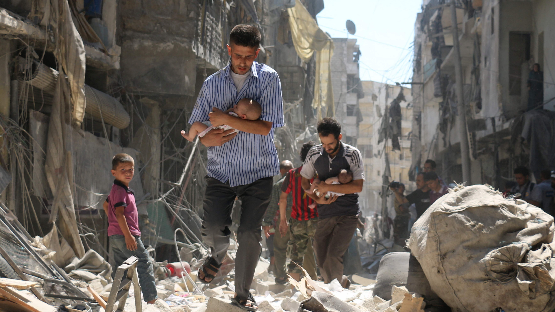 In Aleppo tragen Männer Babys durch eine völlig zerstörte Straße | AFP