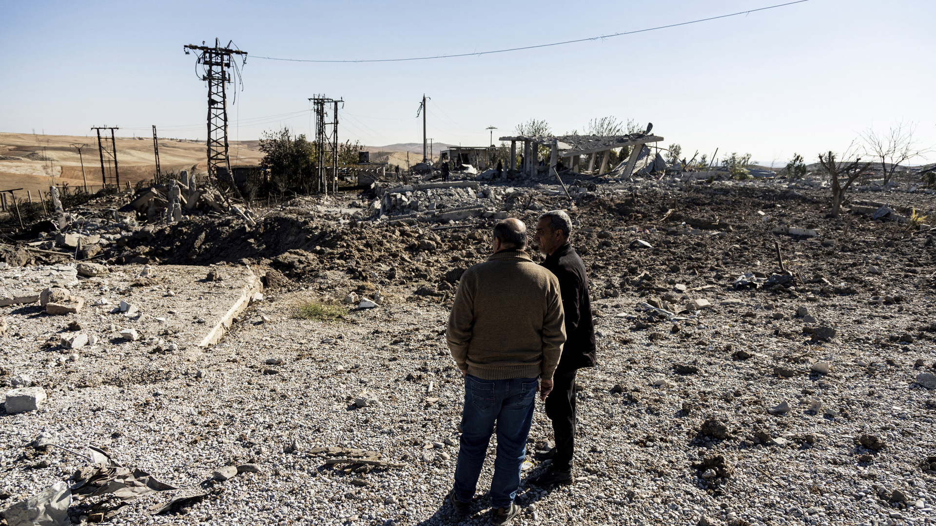 Menschen betrachten im Dorf Taql Baql in der Provinz Hasakeh (Syrien) eine Stelle, die durch türkische Luftangriffe beschädigt wurde. | AP