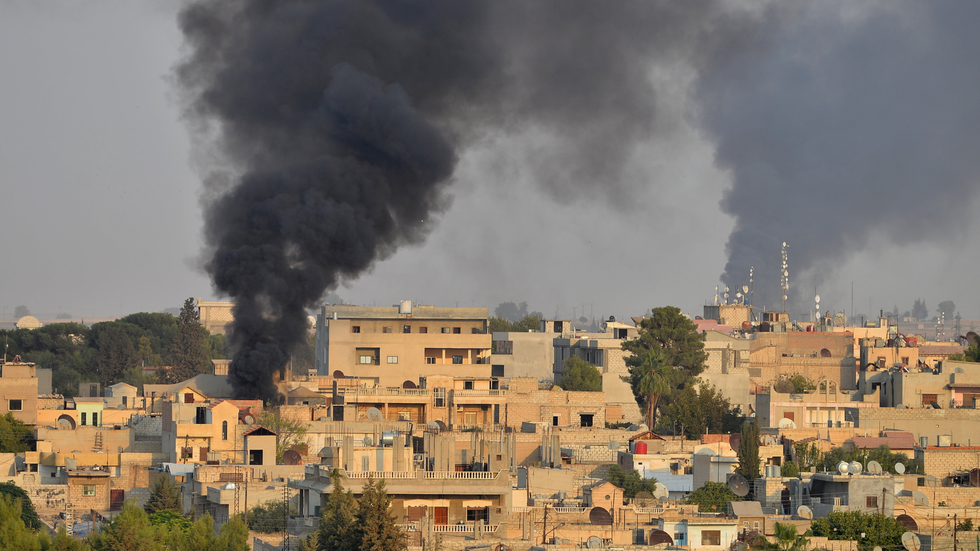 Rauch steigt zwischen Häusern nach einem Bombenangriff über der nordsyrischen Stadt Ras al-Ain auf.