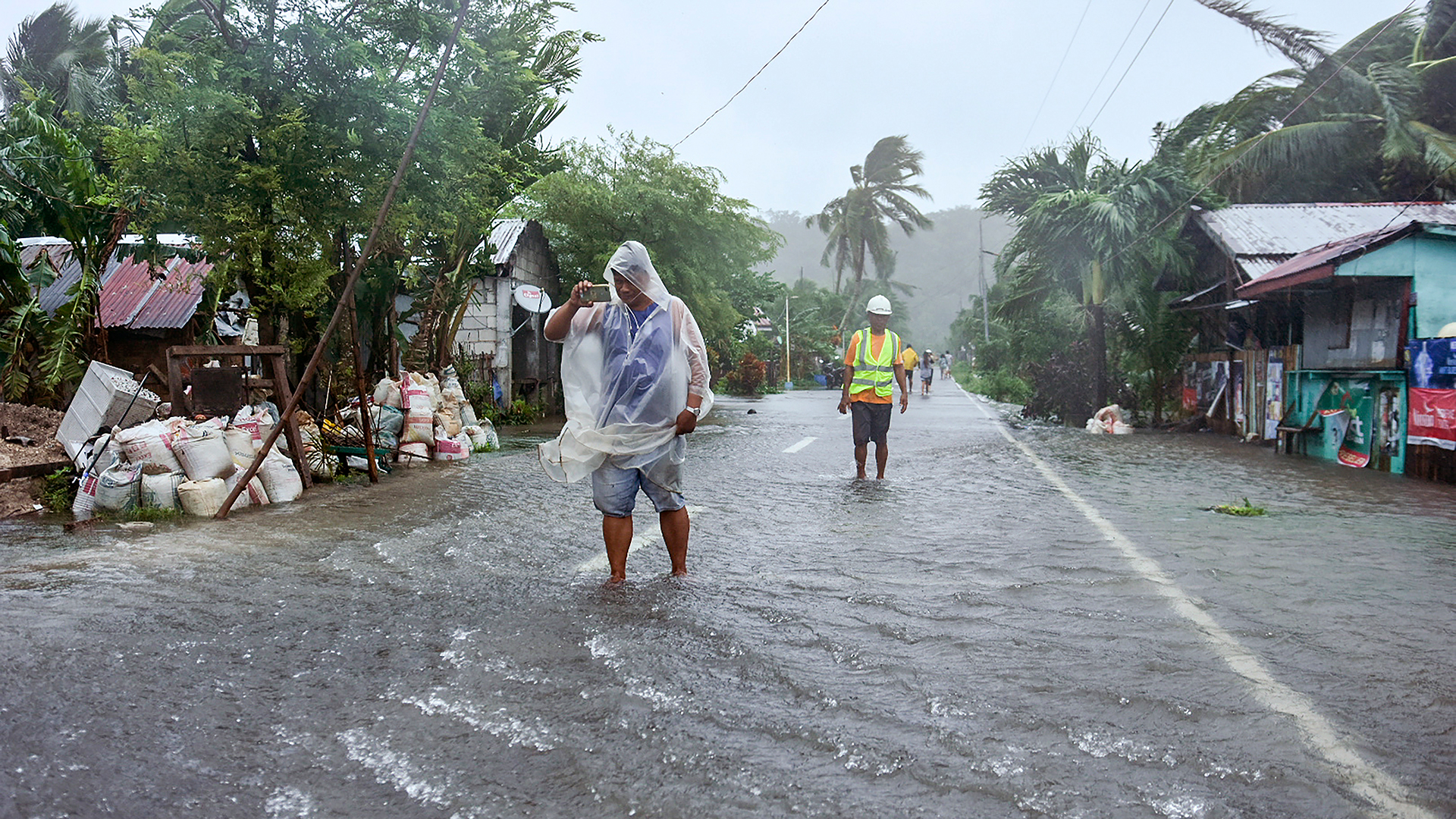 Bewohner waten durch eine vom Taifun "Rai" überflutete Straße.  | picture alliance/dpa/AP