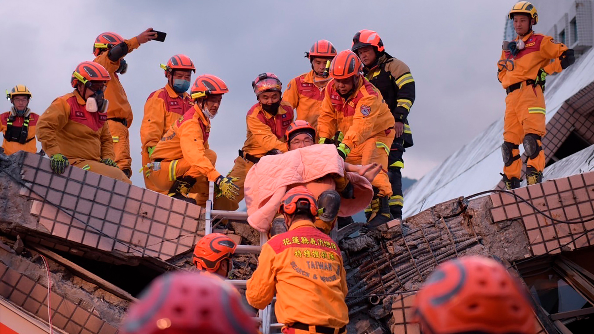 Rettungskräft bei Bergungsarbeiten an einem eingestürzten Haus. | AP
