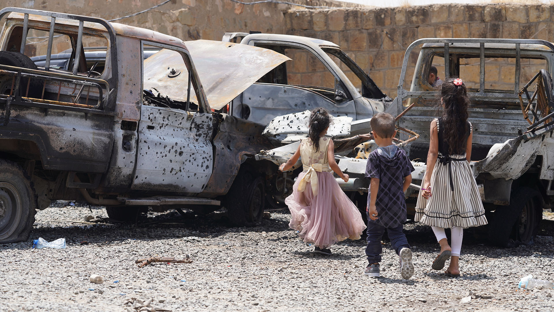 Beschädigte Fahrzeuge und jemenitische Kinder sind nach einem Angriff mit unbemannten Luftfahrzeugen durch die vom Iran unterstützten Huthis in Taiz im Jemen zu sehen. | picture alliance / AA