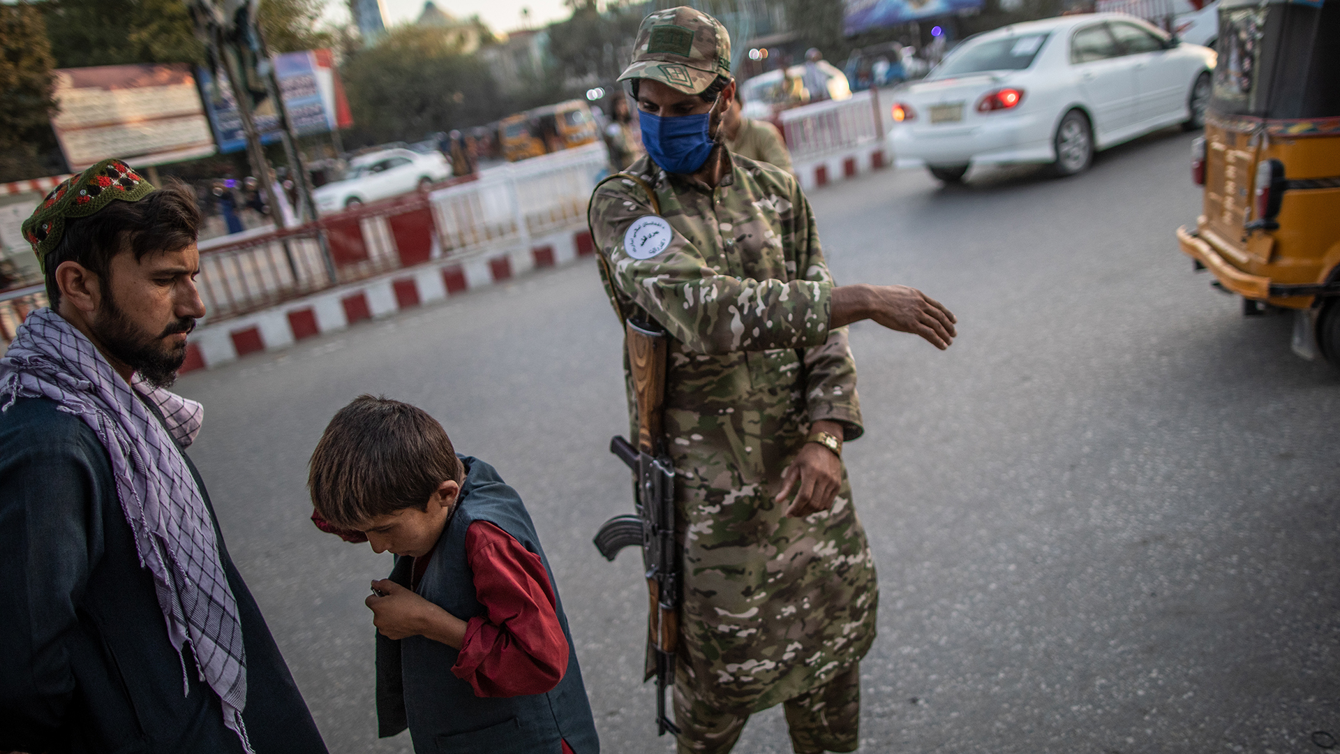 Ein Taliban-Polizist ohrfeigt einen Jungen, der eine Straße in Kundus entlanggeht. | picture alliance/dpa