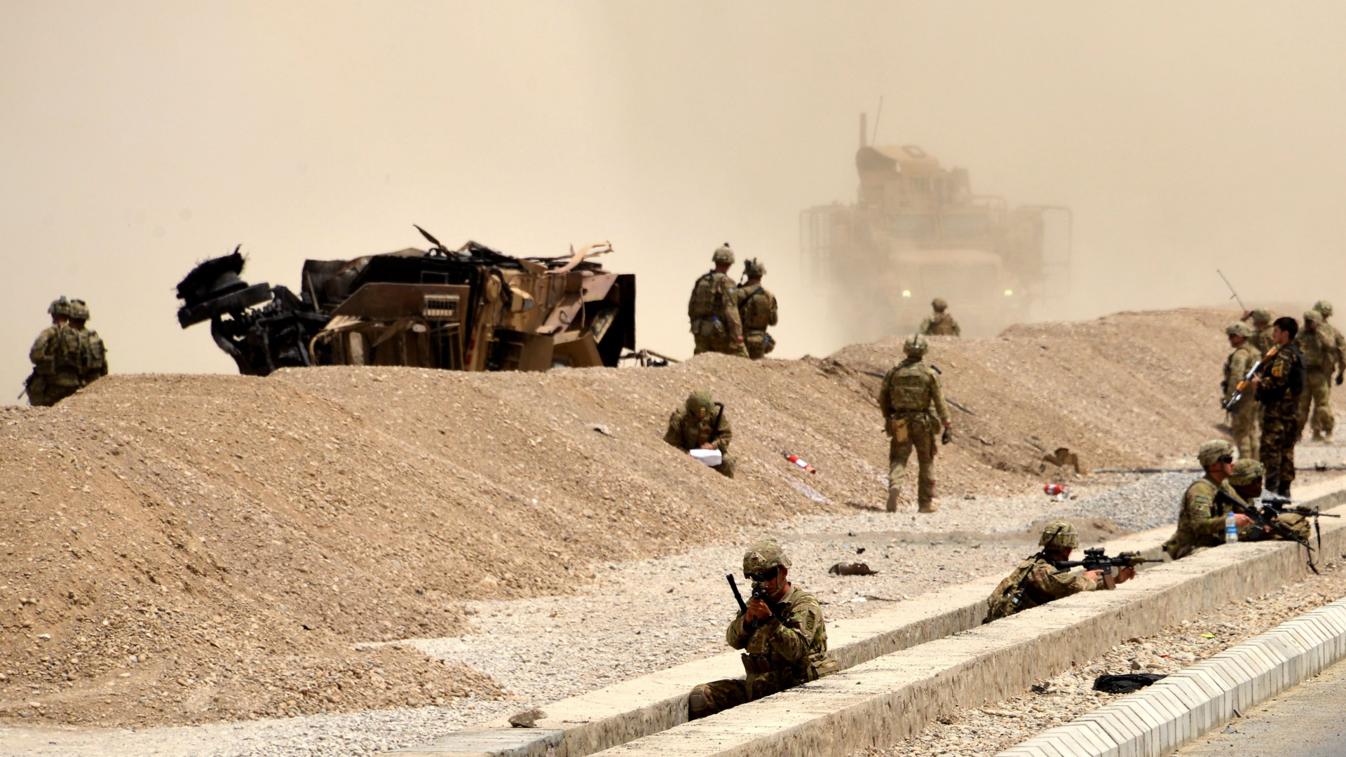 US-Soldaten in Afghanistan umstehen ein Militärfahrzeug, das bei einem Selbstmordanschlag der Taliban explodiert ist (Archivbild). | AFP