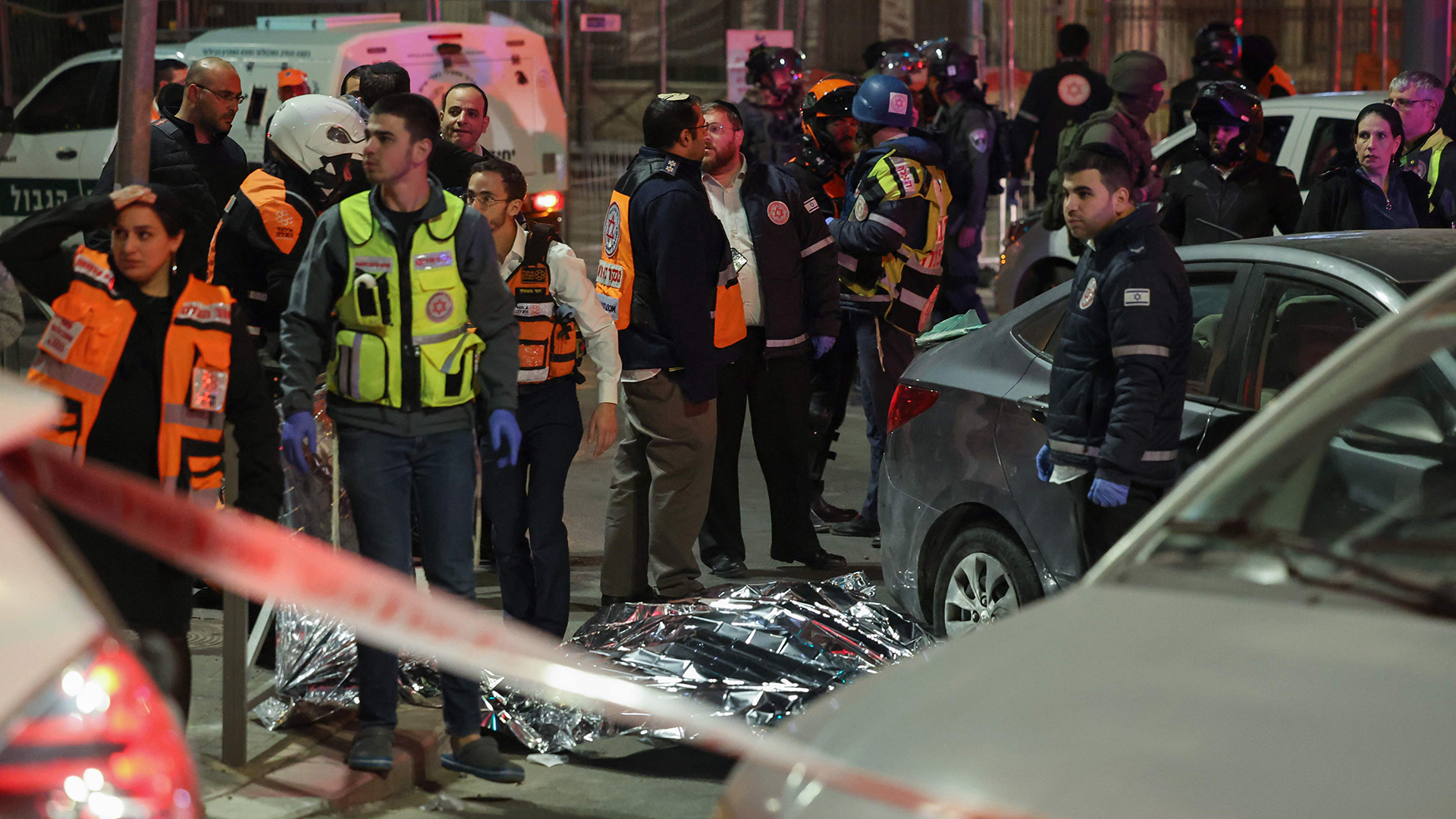 Israelische Rettungskräfte und Sicherheitskräfte stehen neben einer abgedeckten Leiche am Ort eines gemeldeten Anschlags in einem Siedlerviertel im israelisch abgetrennten Ostjerusalem. | AFP