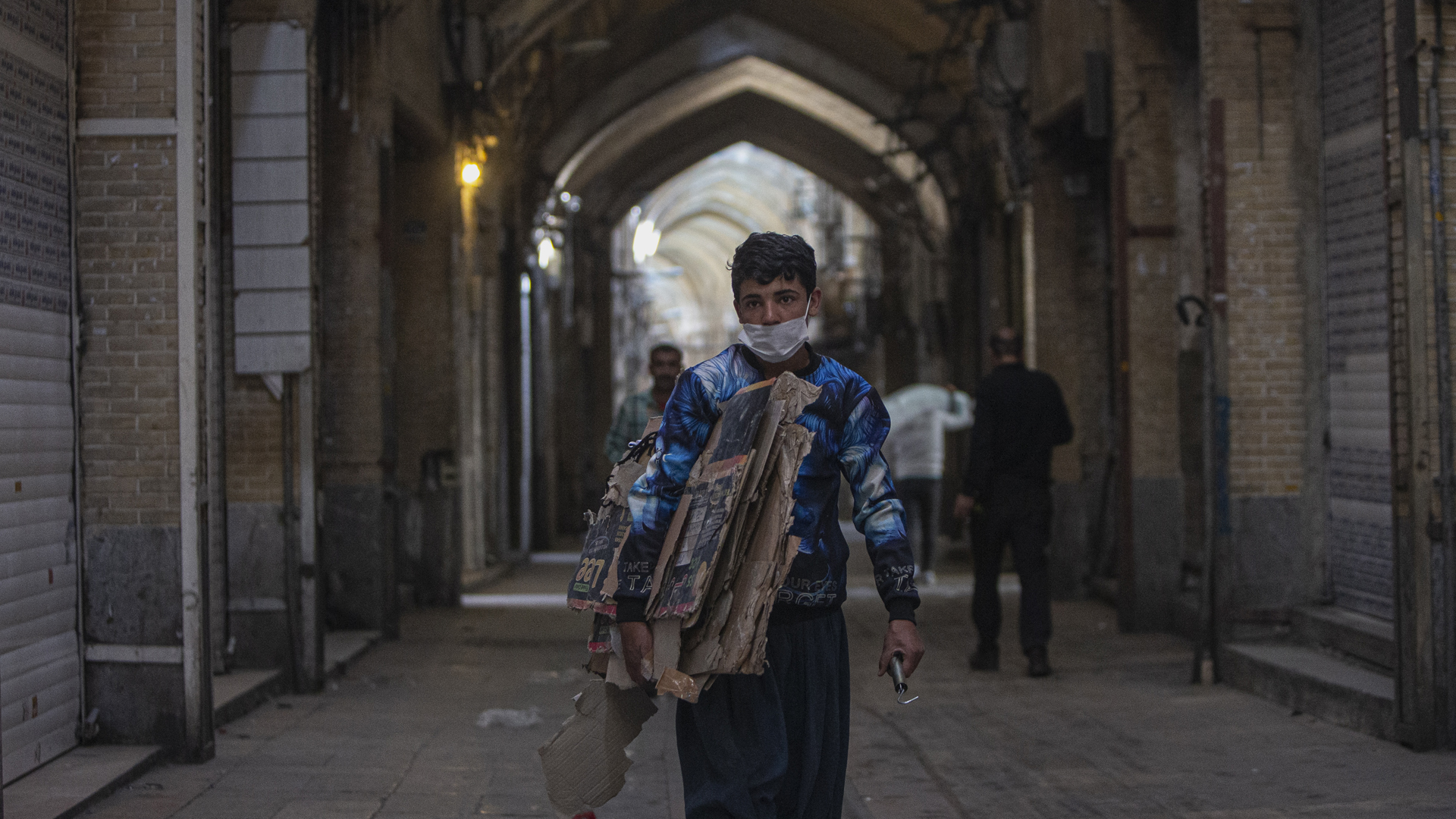 Ein Junge mit einer Gesichtsmaske geht an geschlossenen Geschäften auf dem Großen Basar in Teheran vorbei.