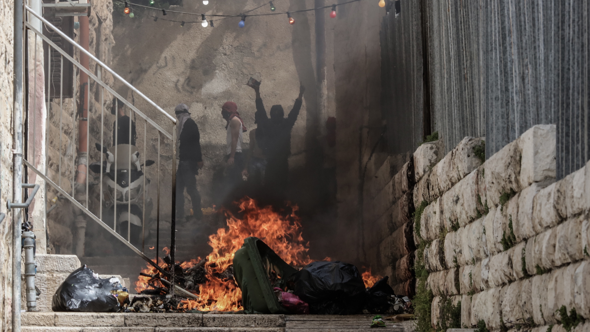Palästinenser stehen hinter einem brennenden Hindernis in der Altstadt von Jerusalem. | dpa