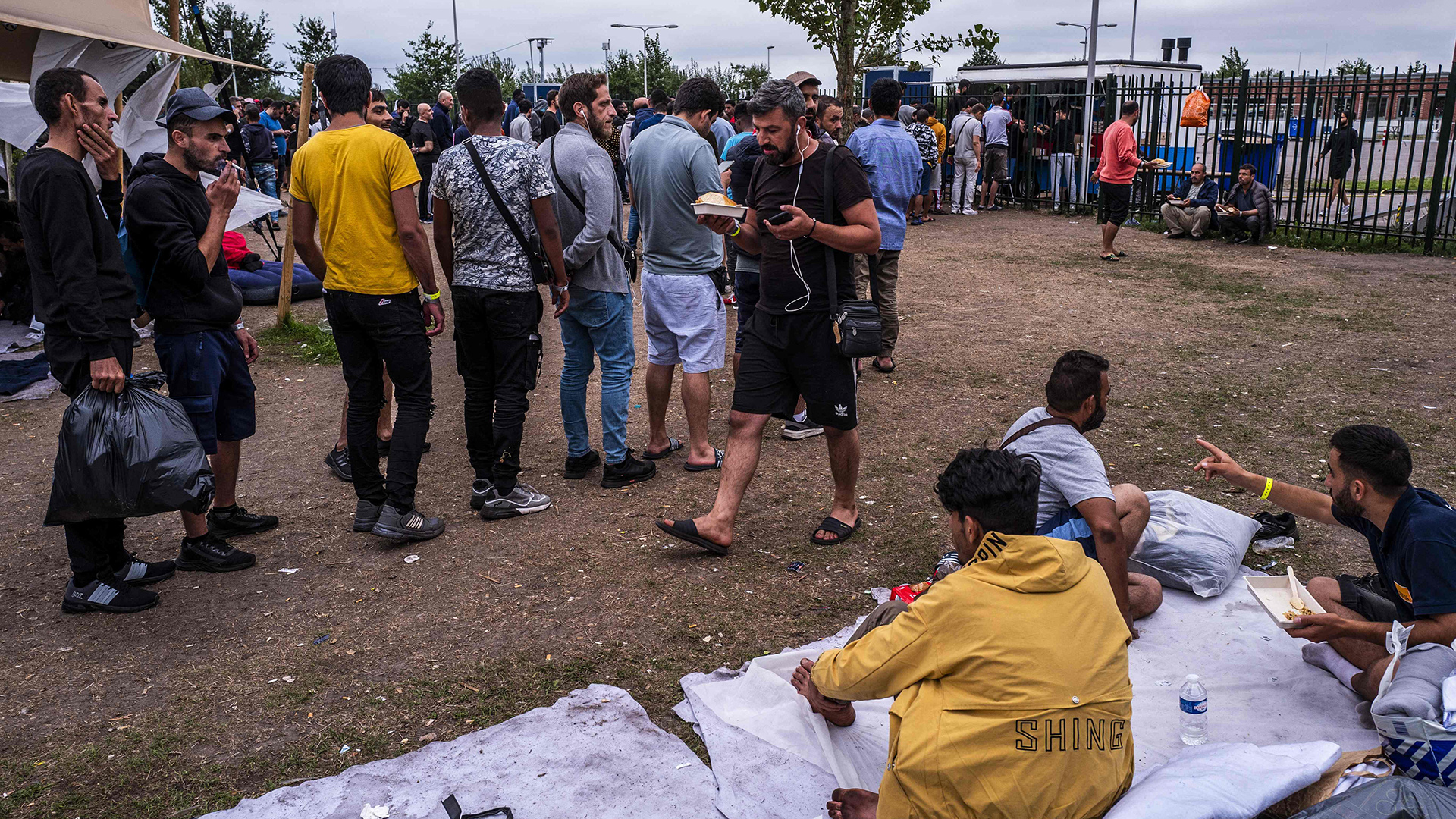 Asylbewerber warten in einer Schlange vor dem Tor des Antragszentrums in Ter Apel auf Essen, Niederlande. | AFP