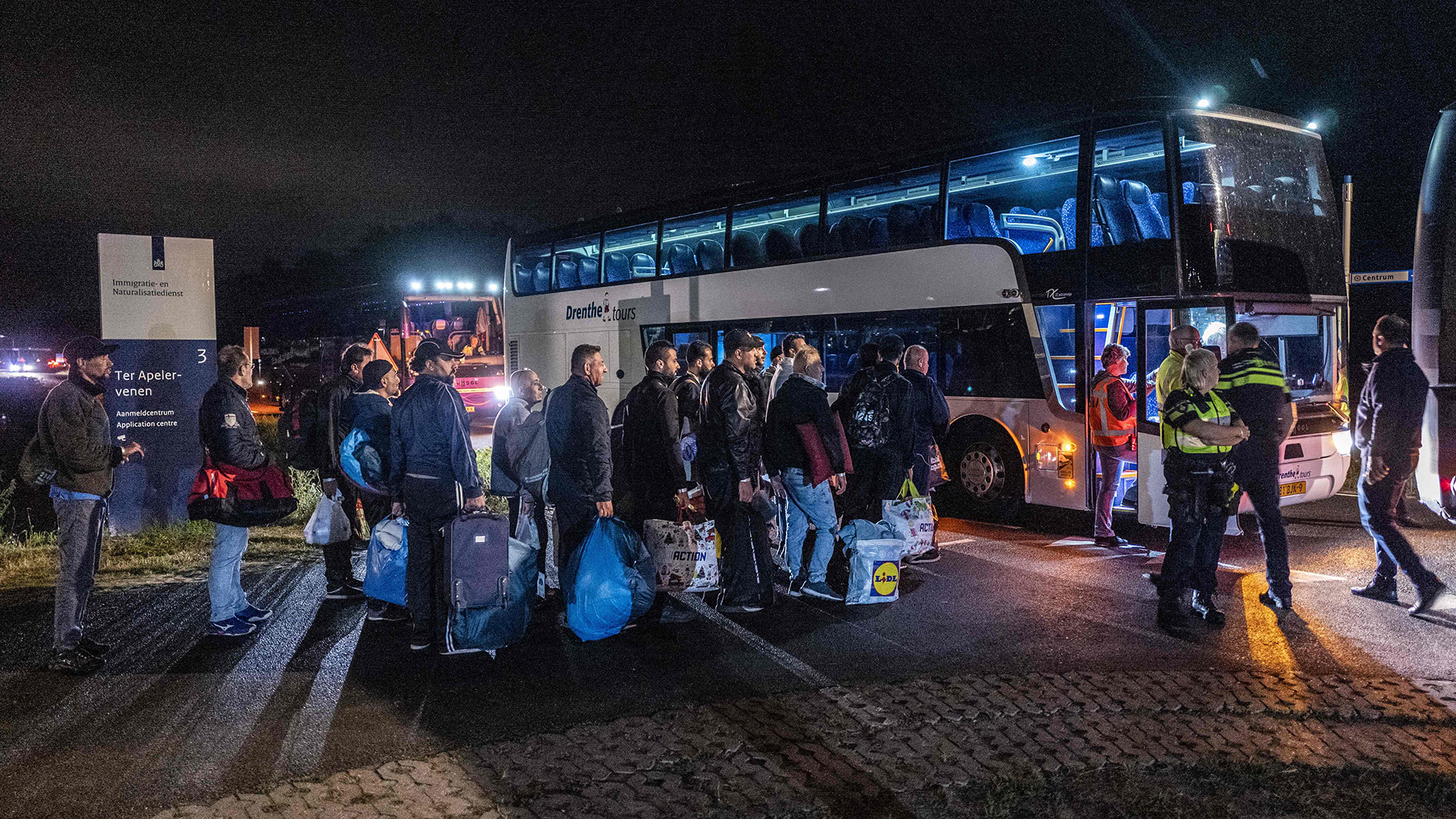 Migranten steigen außerhalb des niederländischen Asylzentrums in Ter Apel in Busse.  | AFP