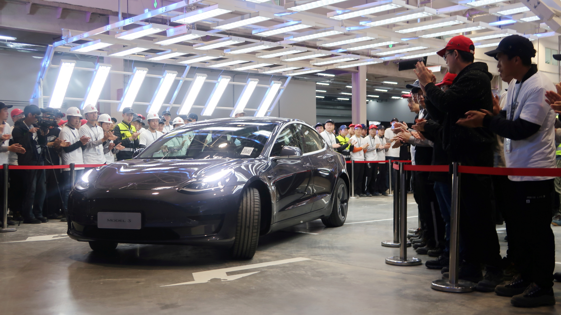 Tesla-Mitarbeiter klatschen bei der Übergabe eines im neuen Werk in Shanghai gefertigten Elektroautos. | REUTERS