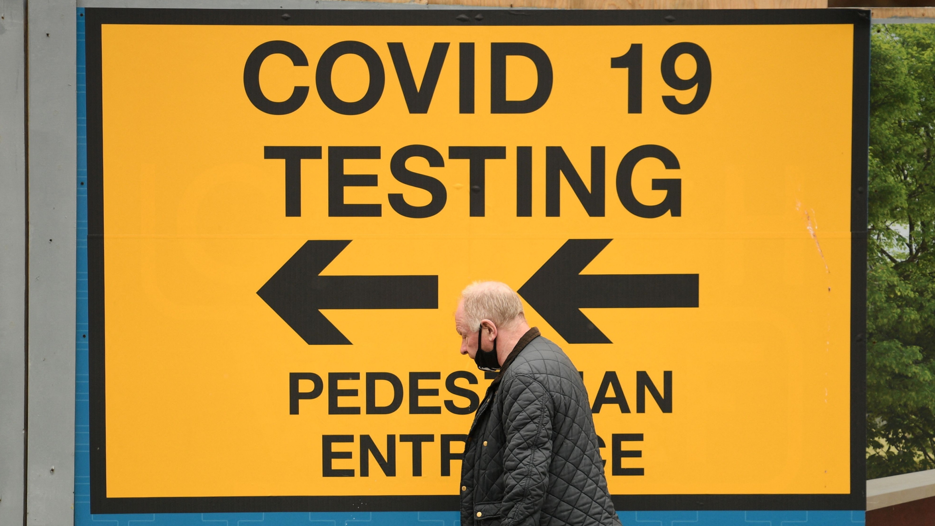Ein Mann geht an einem Schild vorbei, das den Weg zu einer Covid-19-Teststation im englischen Bolton zeigt. | AFP