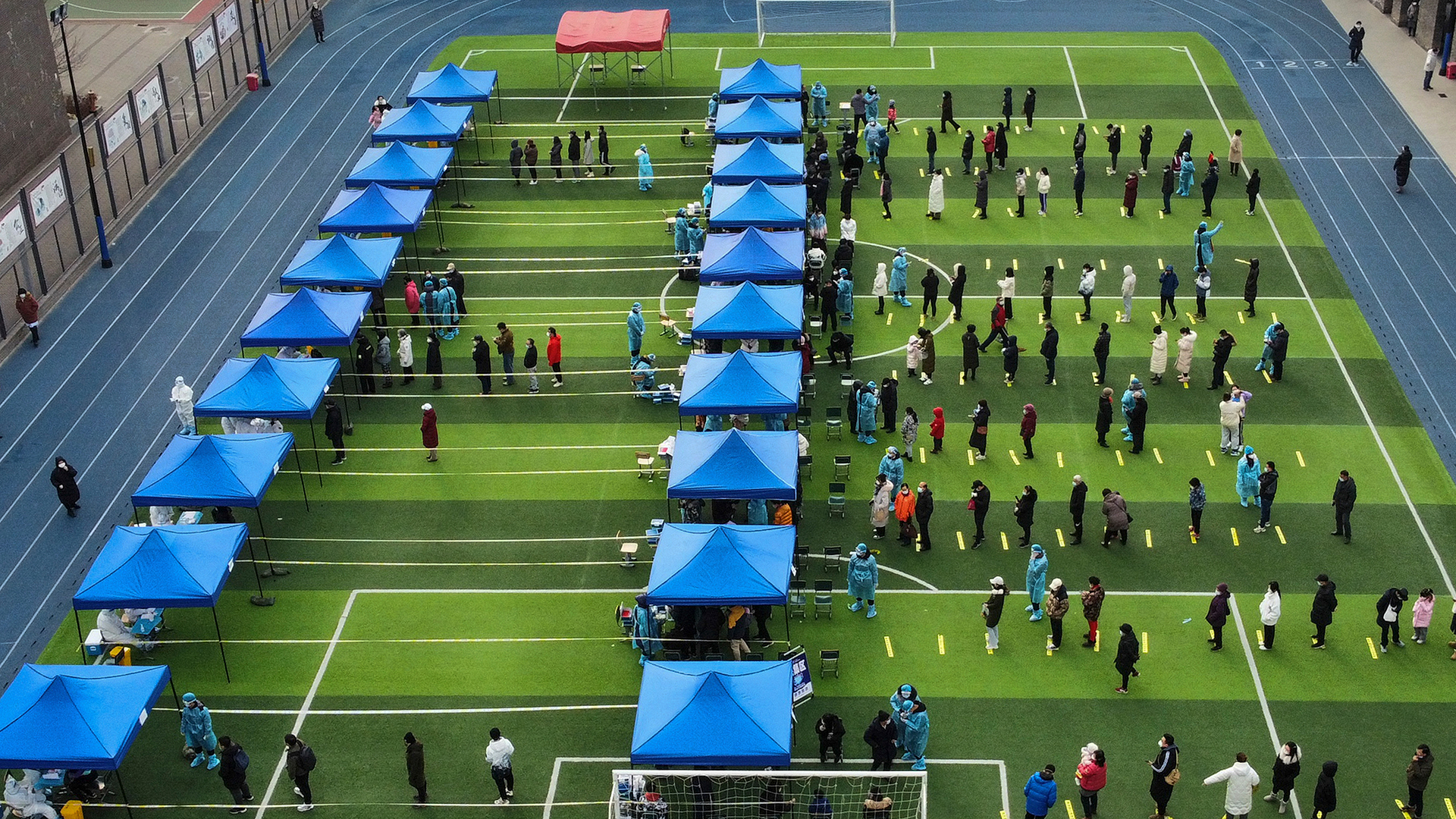 Einwohner von Tianjin stehen auf einem Fußballfeld für einen Corona-Test während eines Massentests Schlange. | dpa