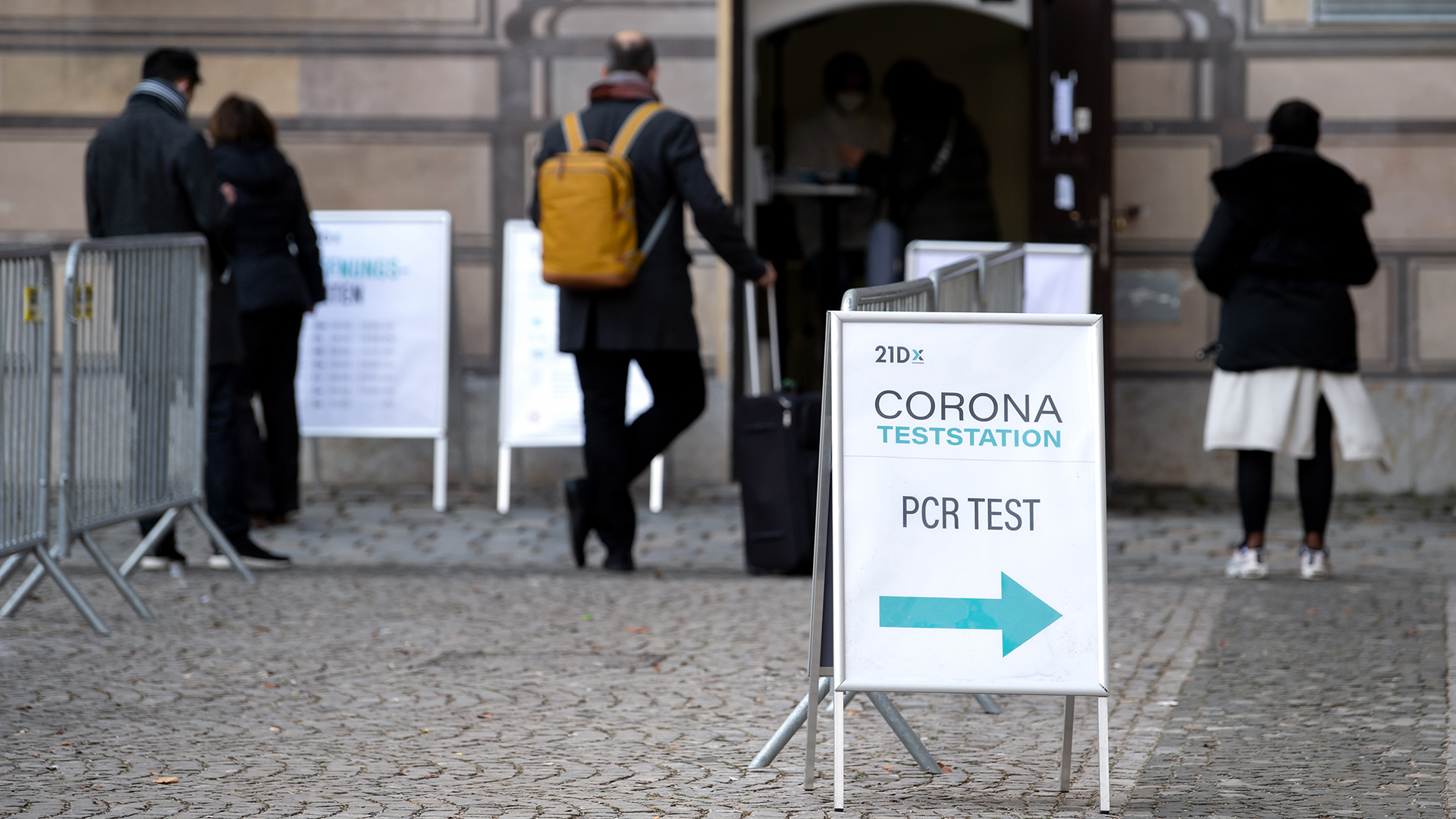 Menschen warten vor einem Corona-Testzentrum in der Bad Homburger Innenstadt auf ihren kostenlosen Covid-Test. | dpa