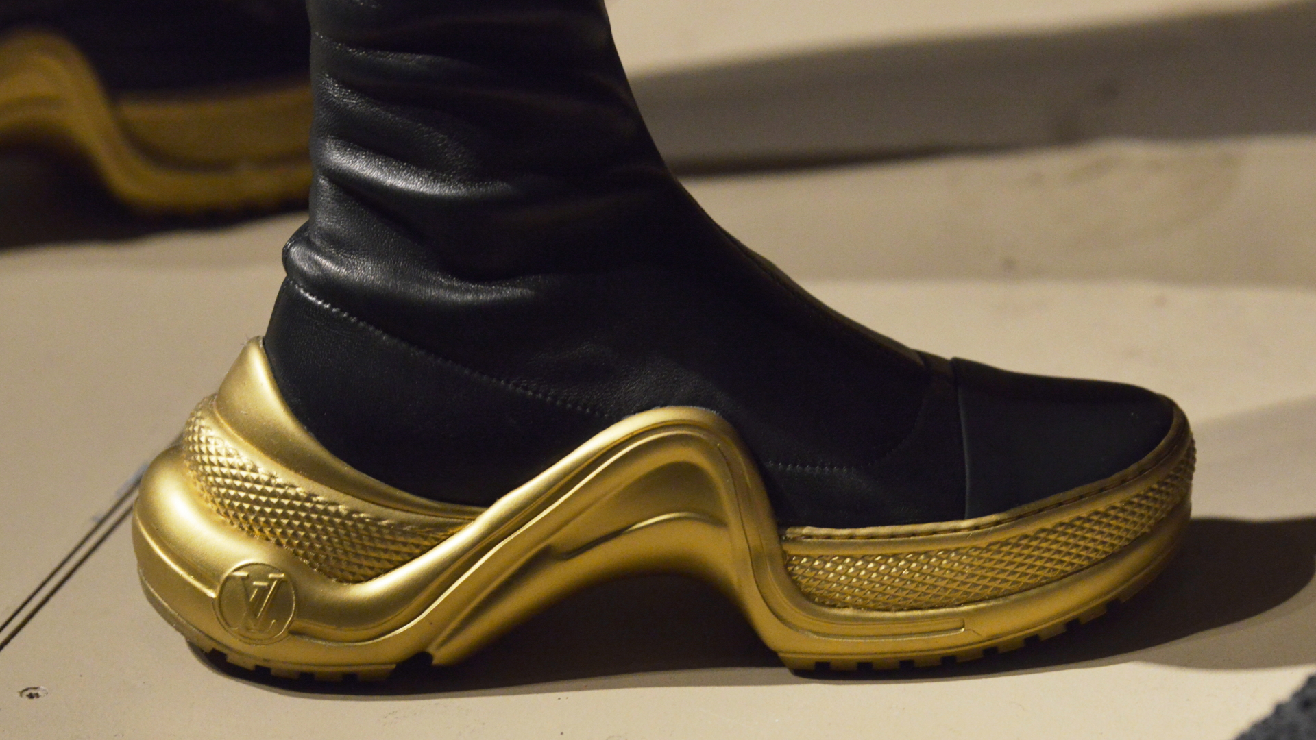 Ein Gast der Fashion Week in Berlin trägt einen Sneaker mit goldener Sohle. | dpa