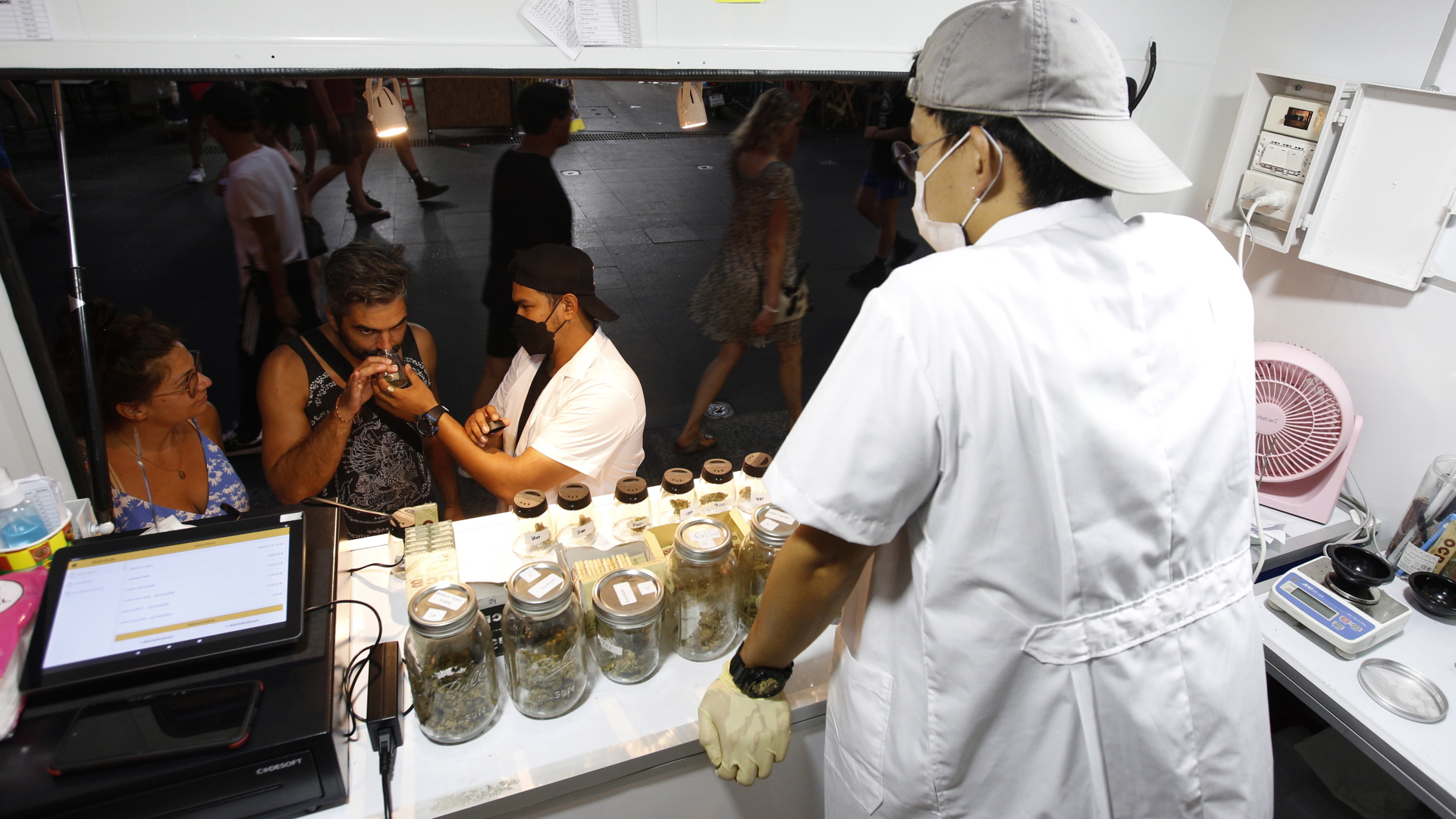 Touristen in Bangkok an einem Stand, der Cannabisprodukte verkauft