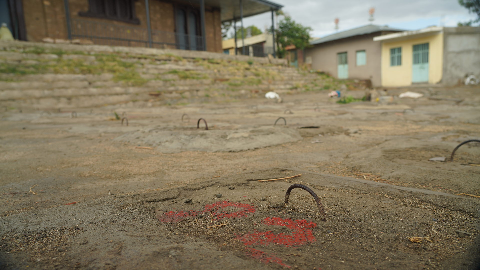 Vor einem Gebäude sieht man mehrere Drahtbügel in Zement befestigt. | Norbert Hahn